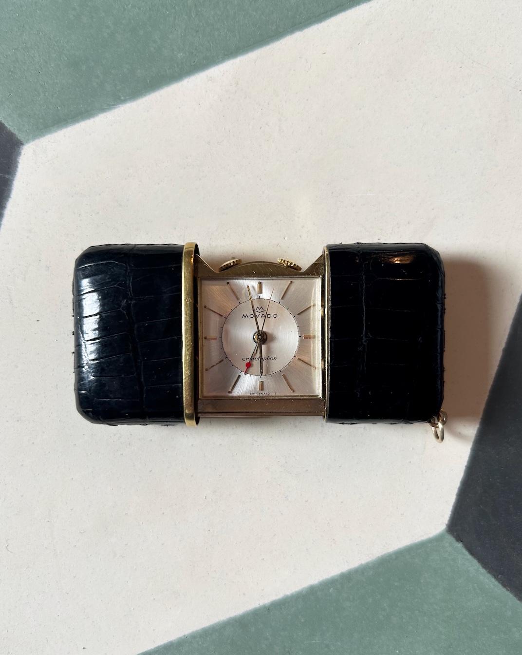 A Movado ‘Ermetophon’ purse watch with alarm. Black crocodile skin with git mounts. 1960s.
In excellent condition with code numbers punched on the back of the case and the original gilt metal strut, movement running well. 
Size open 76mm x 38mm.