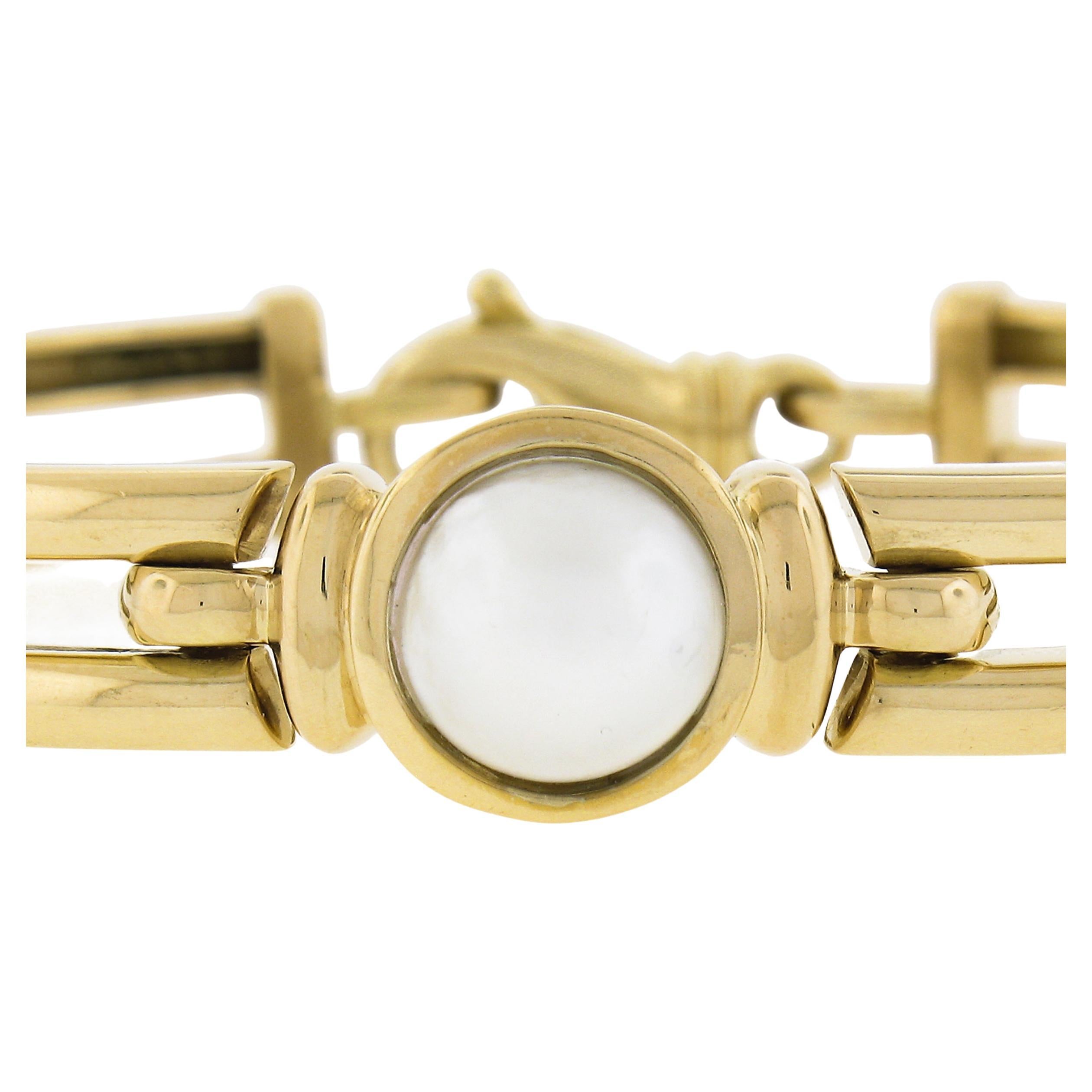 A lovely contemporary piece signed for Movado and crafted in solid 18k gold. Hefty and has some nice weight to it. Dual hinged gold wires with a bezel set white mabe pearl centerpiece that is a classic design from the Harmony collection by Movado.