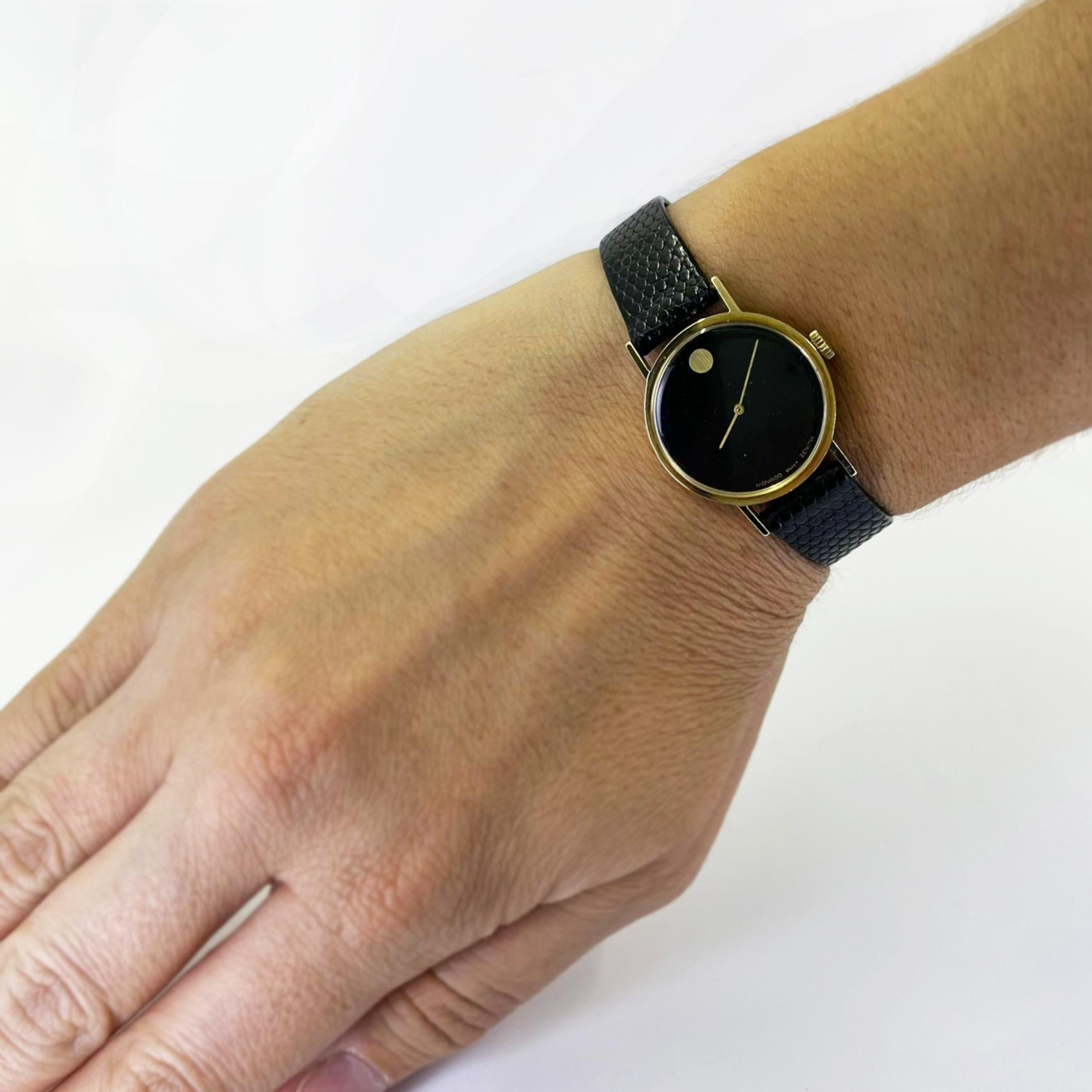 Pre-owned 24mm Movado manual watch crafted in 14 karat yellow gold with black dial on original black lizard strap with tang buckle.