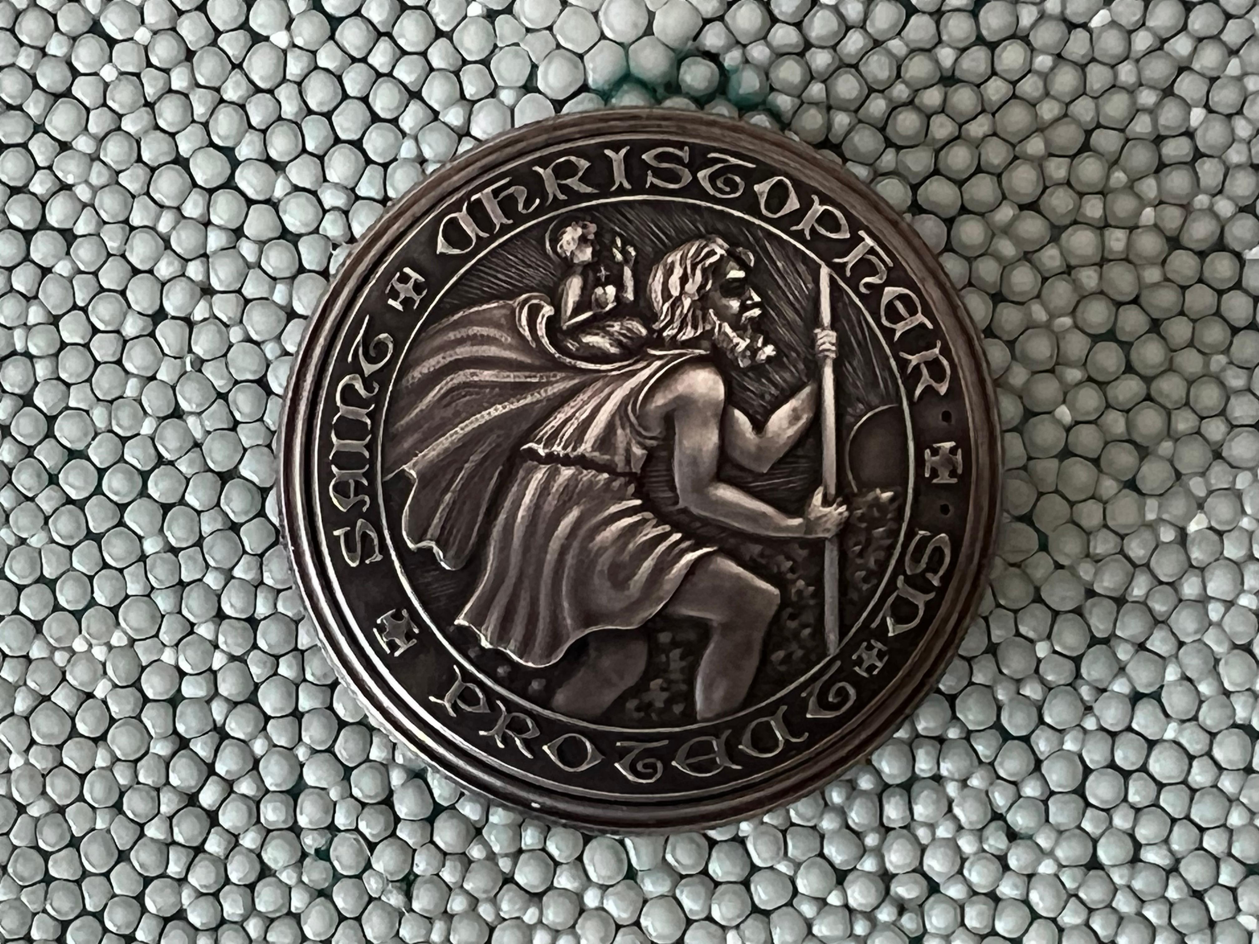 An unusual sterling silver coin watch by Movado ca' 1950's-60's. Dial double signed by Turler-the famed Swiss retailer. Saint Christopher was a patron saint of travellers.