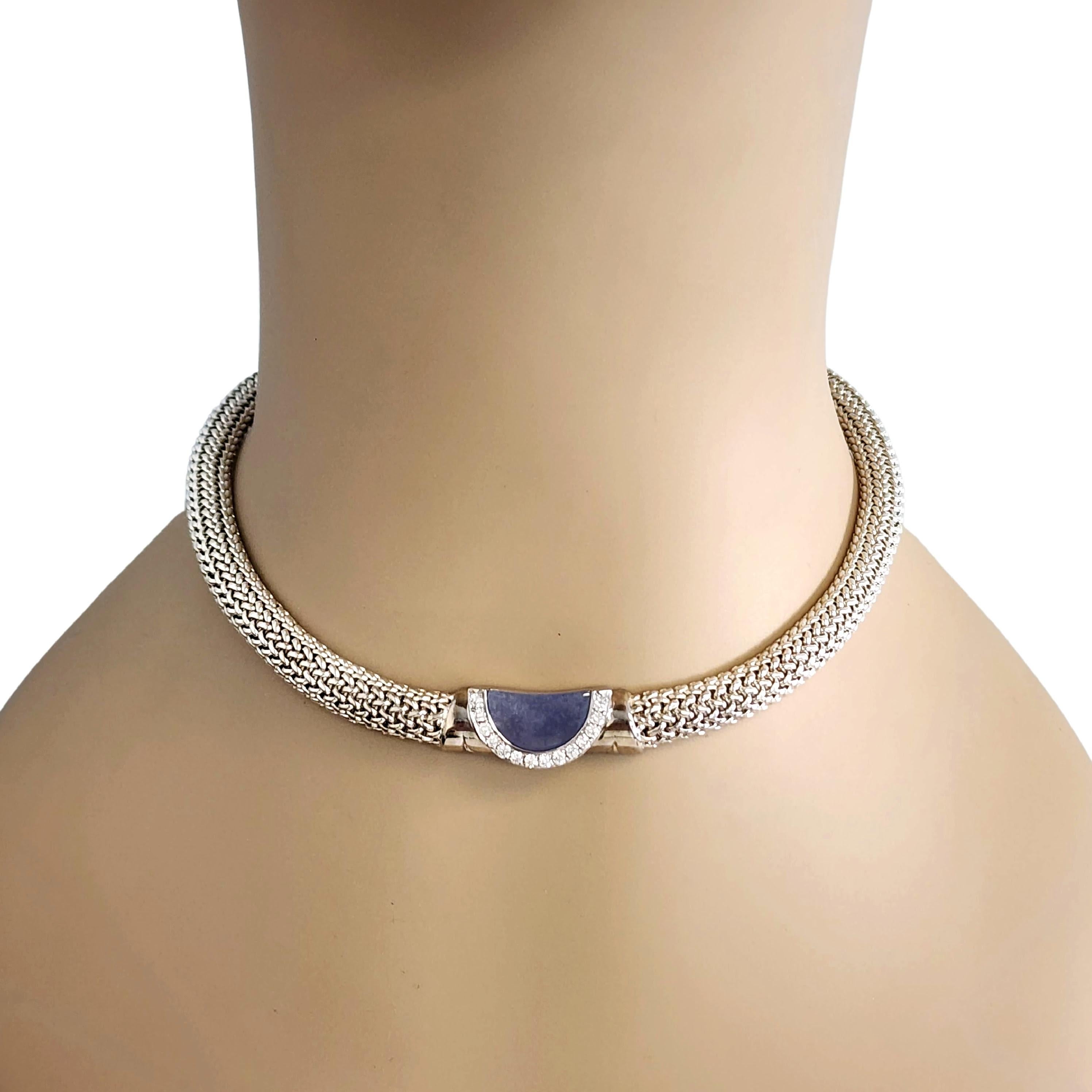 Movado sterling silver 18K white gold chalcedony and diamond mesh choker necklace.

This elegant necklace features a sterling silver mesh chain with a 18K white gold center featuring a half moon purple chalcedony stone with an arc of 14 small round