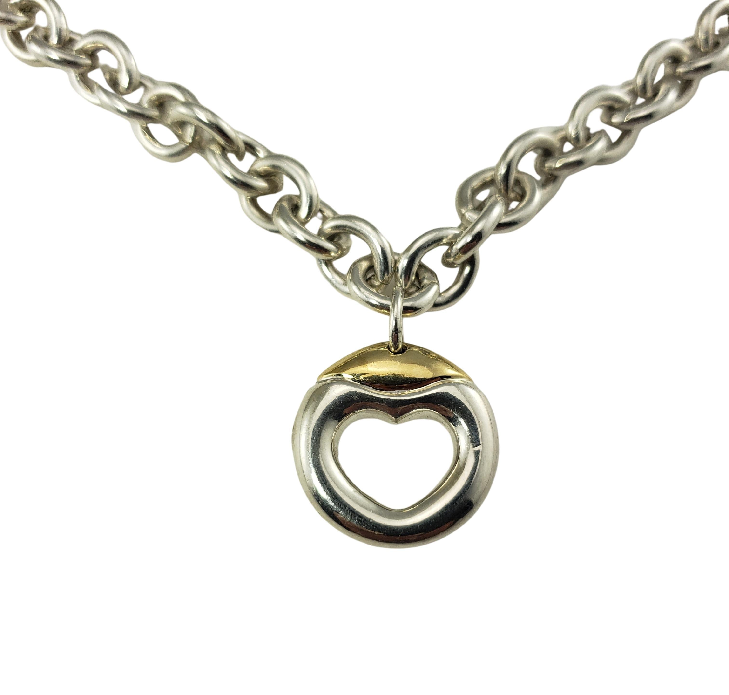 Movado Sterling Silver and 18 Karat Yellow Gold Heart Necklace-

This open heart pendant is crafted in sterling silver and 18K yellow gold and suspends from a sterling silver link necklace (Chain 
Width: 7 mm).

Size:  16 inches
         19 mm x 19