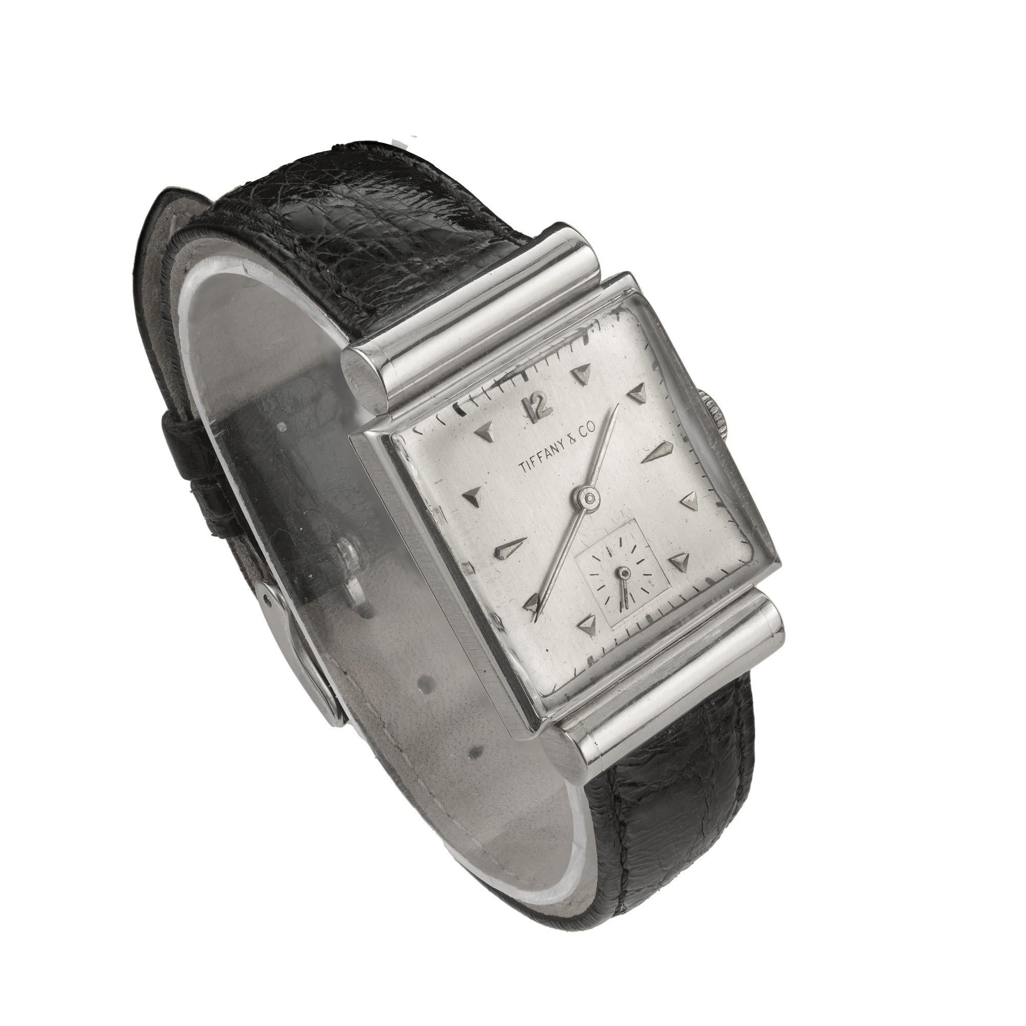 Découvrez l'élégance intemporelle avec la montre-bracelet Movado en platine de forme carrée avec cornes à capuchon, circa 1953, vendue par Tiffany & Co.  Ce garde-temps exquis est un mariage de sophistication et de savoir-faire, faisant écho à