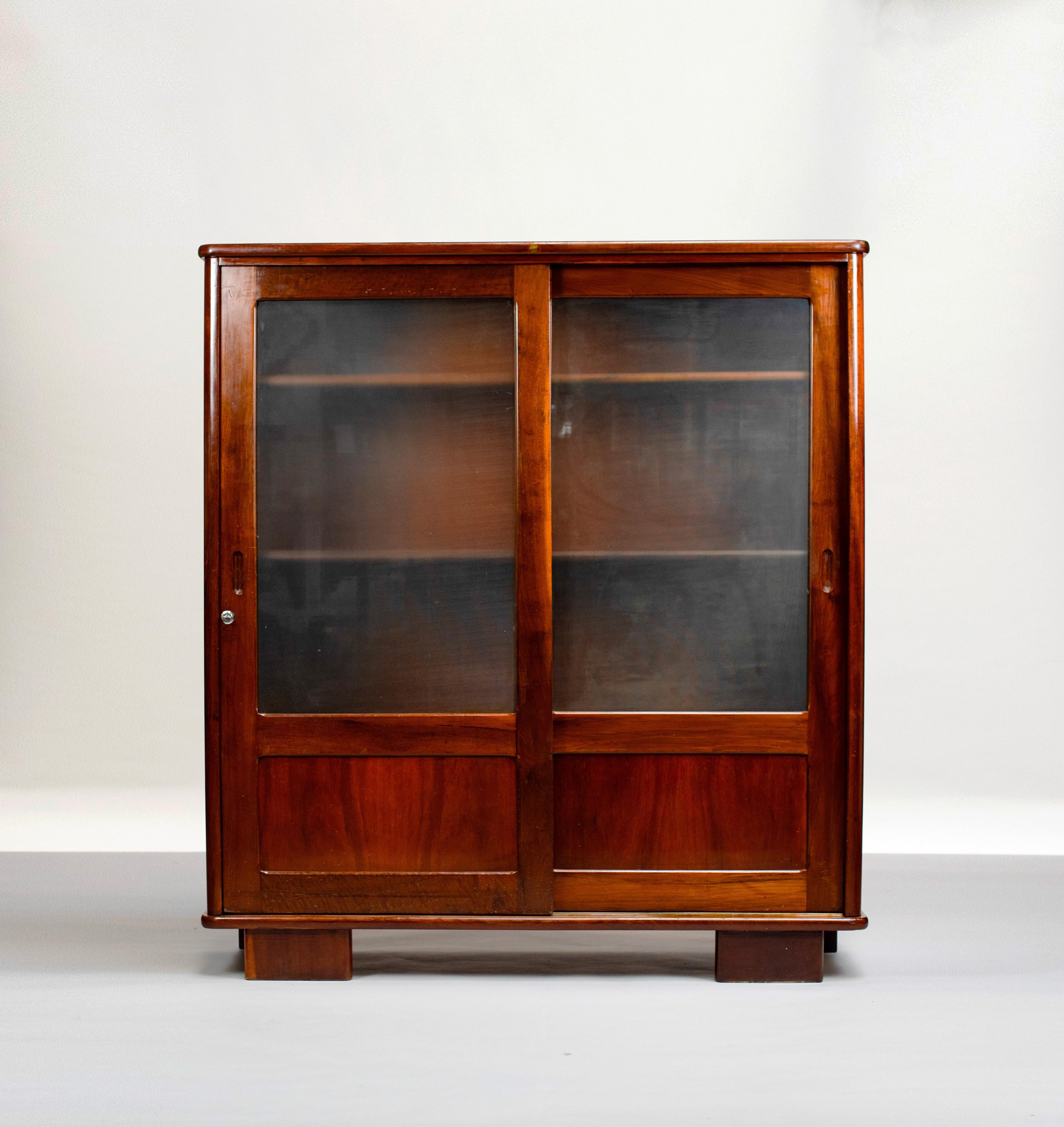Wooden bookcase by Imbuia's wood, an exotic species of Brazil very appreciated for its warm natural hue and the finesse of its grain. This room has two sliding doors in Imporia wood and opalescent glass. 

The handles are created from notches cut