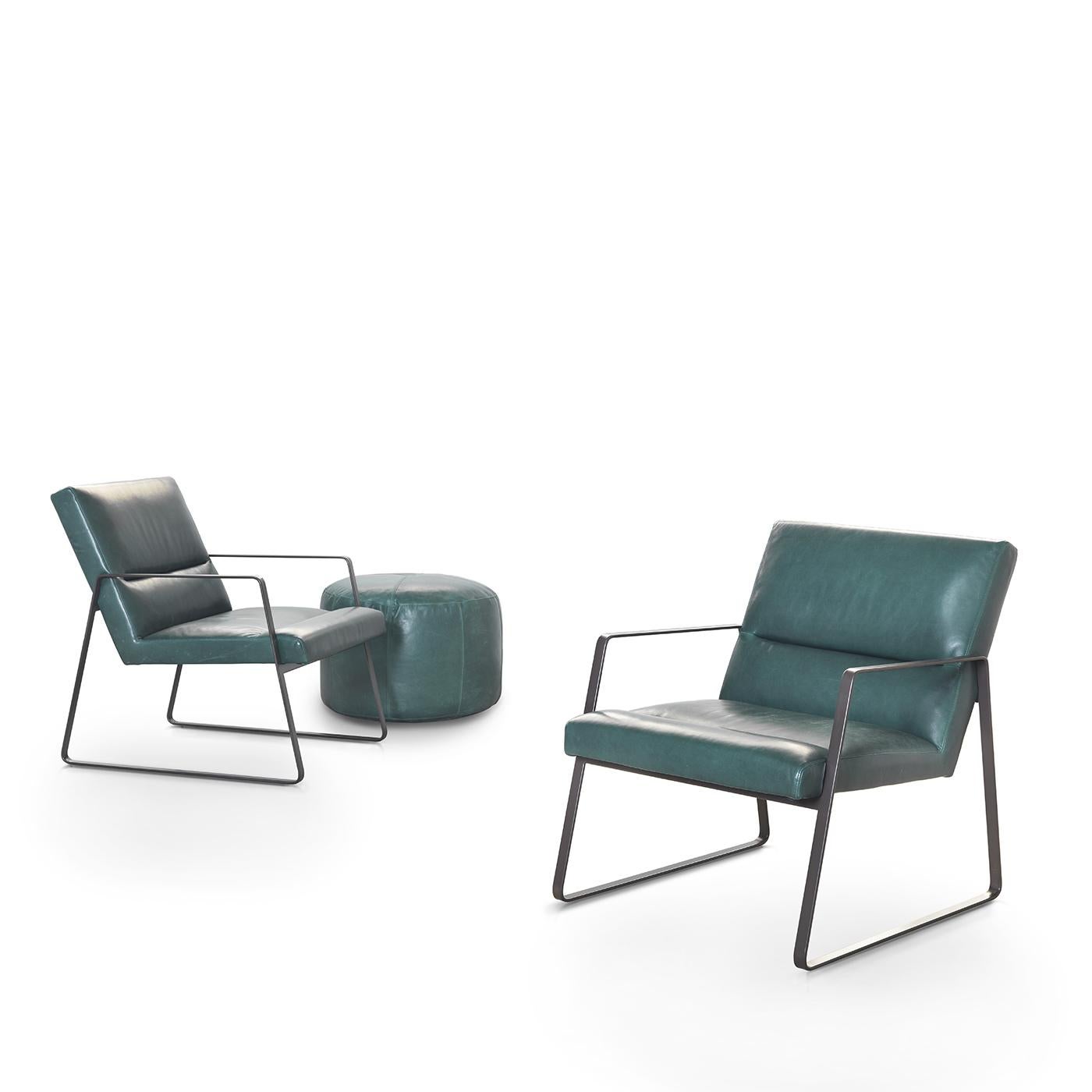 The sophisticated lines and contemporary structure of this emerald green leather armchair is almost reminiscent of a movie theater seat with its slightly-reclined backrest. Large minimal metal trapezoids serve both as armrests and a base for the