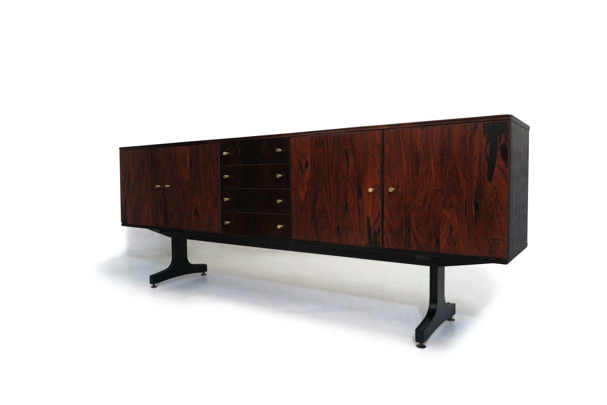 Movies Cimo, Brazilian Credenza, 1960, crafted of rosewood with four doors, and series of four drawers in center with brass pulls opening to reveal an interior of Pau Marfim wood. Painted black side panels and raised on trestle legs. Good vintage