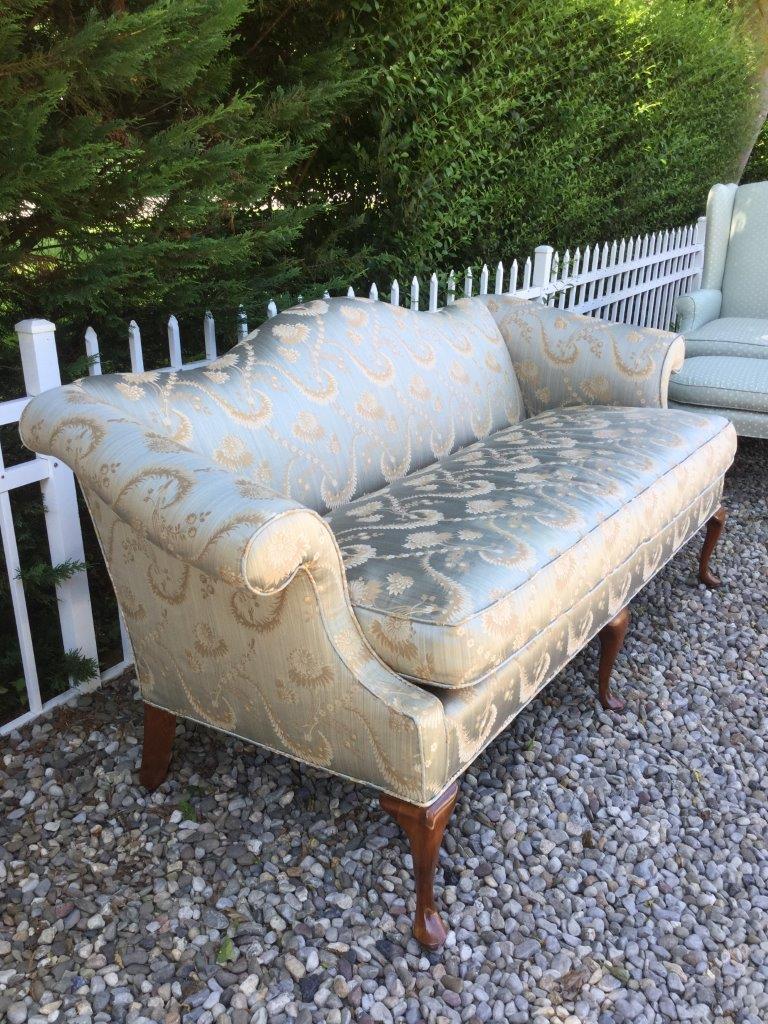 Elegant and quality describe this blue silk settee. Custom upholstered, this English style sofa features a camelback and rolled arms. There is a single seat cushion which is deep and comfortable. The silk fabric is soft blue with a green tinge, with