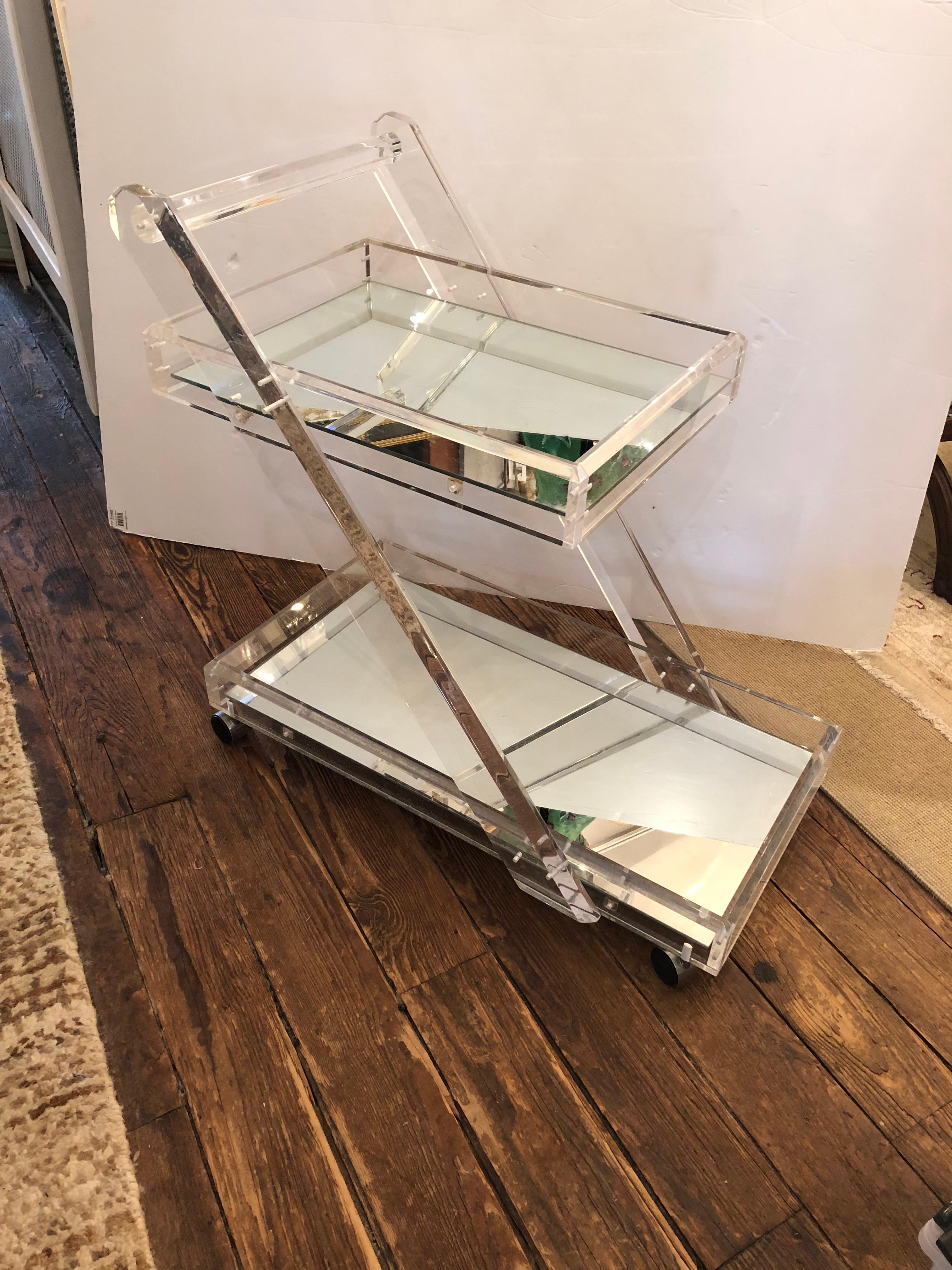 Glitzy Mid-Century Modern two tier lucite bar cart having mirrored surfaces and easily gliding casters.
Measure: Top shelf 24