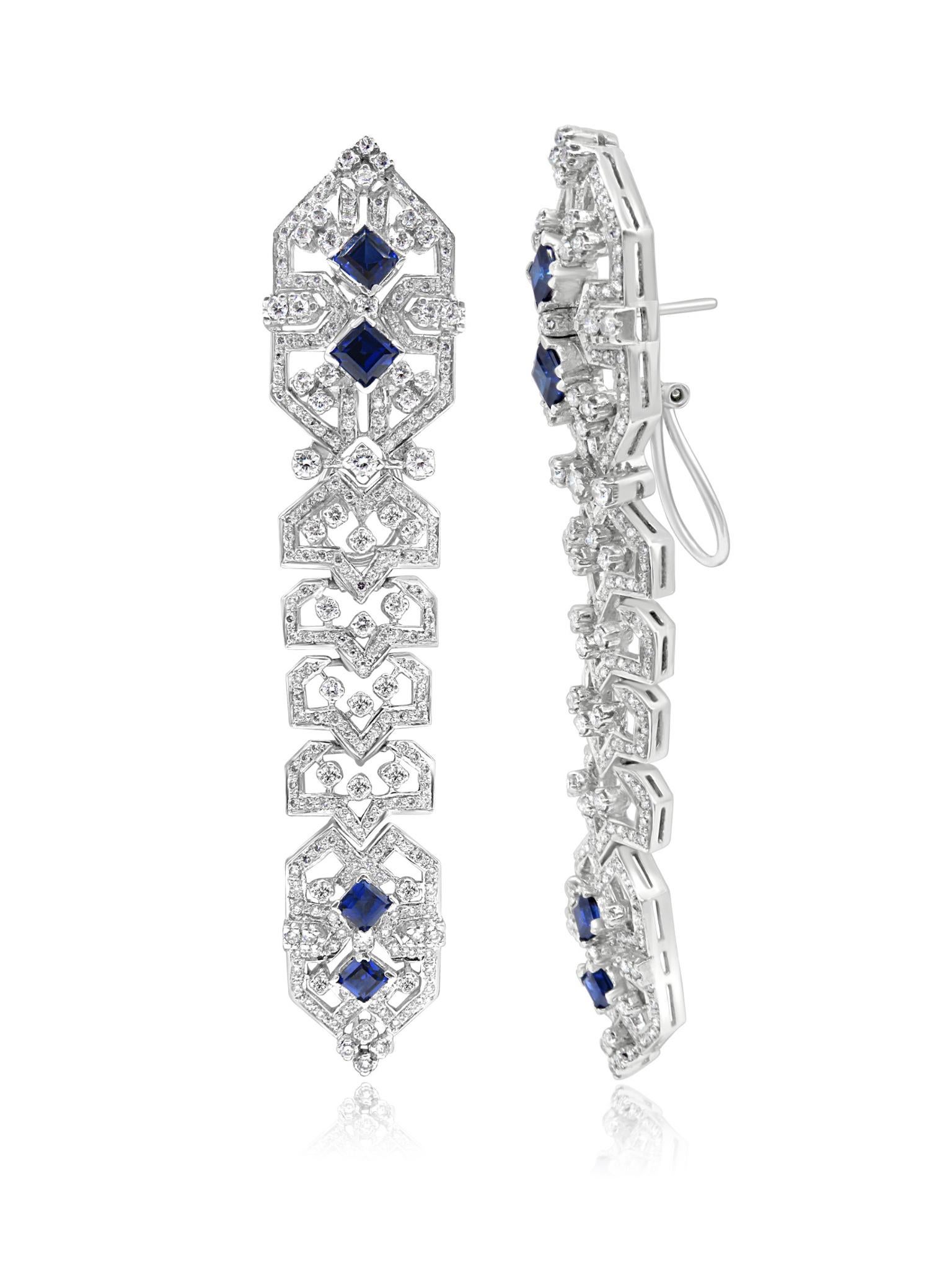 Splendidi orecchini in oro bianco 18 carati impreziositi da diamanti e zaffiri blu. L'intricato design presenta un motivo simmetrico con zaffiri blu taglio principessa incastonati al centro e circondati da diamanti scintillanti. I dettagli