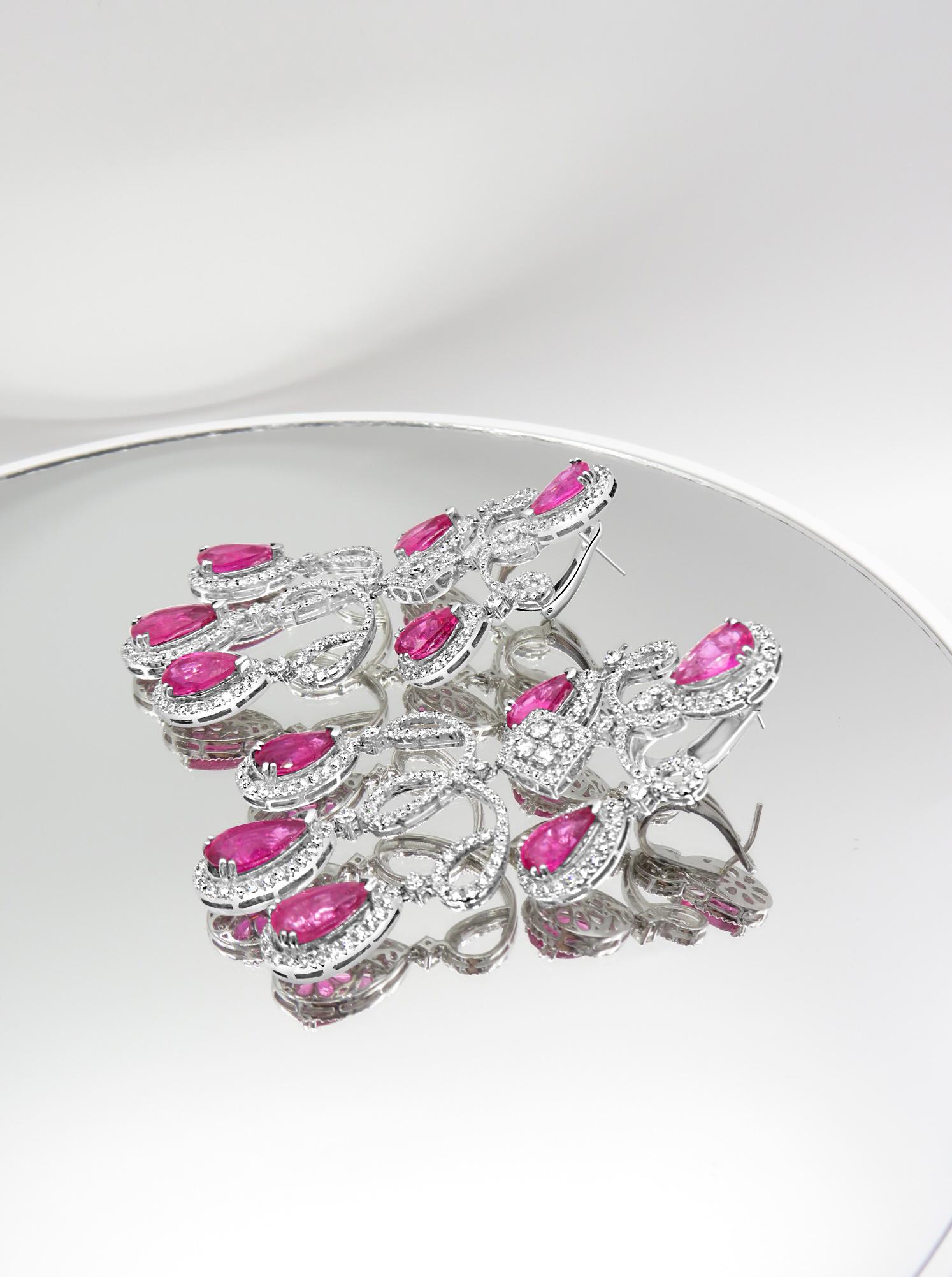 Stunning chandelier earrings featuring an intricate design crafted from 18-karat white gold. They are adorned with dazzling white diamonds that beautifully contrast with the vibrant rose-hued rubelites. Designed in a classic chandelier style, the
