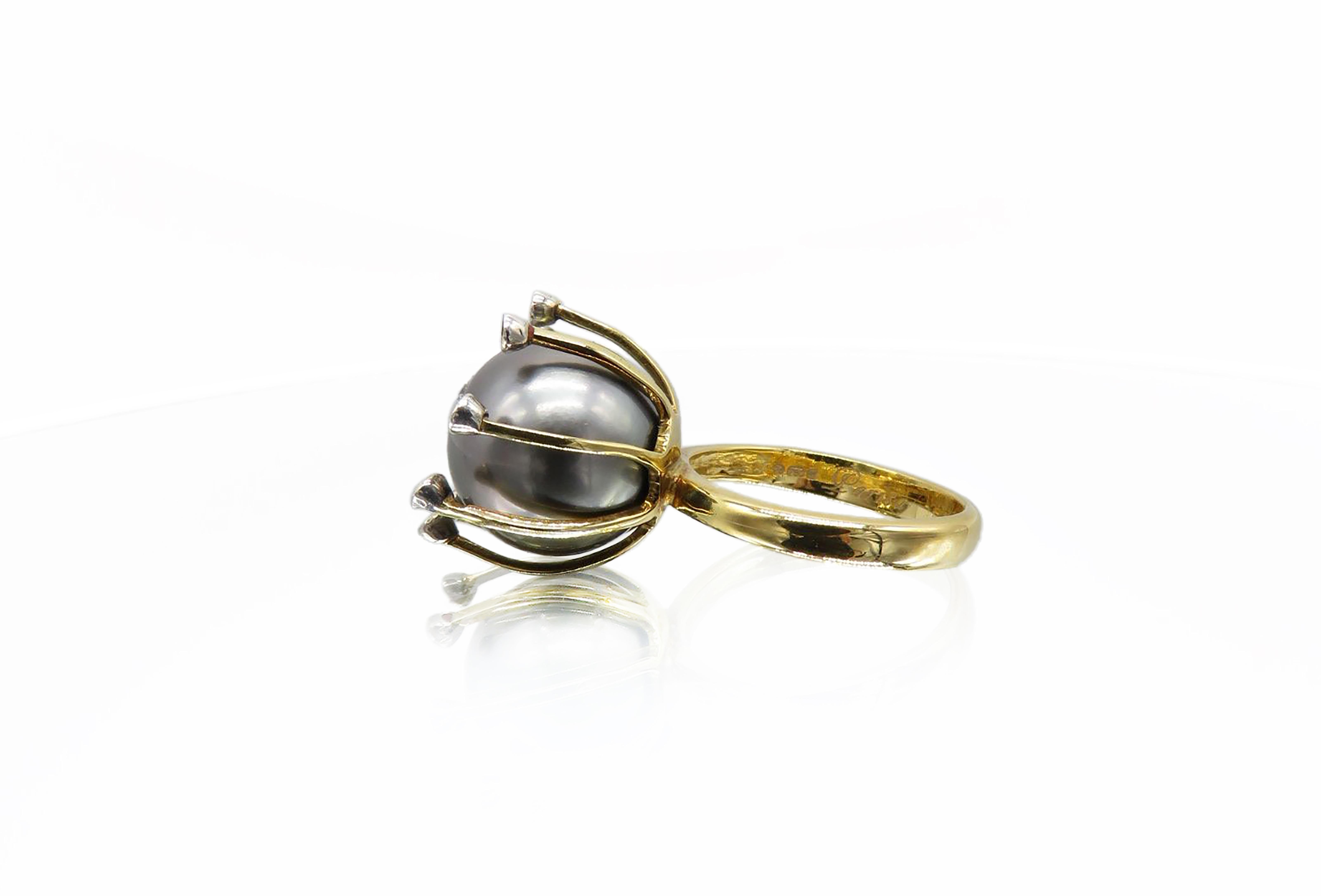 Crafted in radiant 18K yellow gold, this stunning ring features a deep, lustrous Tahiti pearl as its centerpiece. Slim gold prongs gently rise to hold the pearl in place, each one crowned with a sparkling white diamond. Elegant and eye-catching,