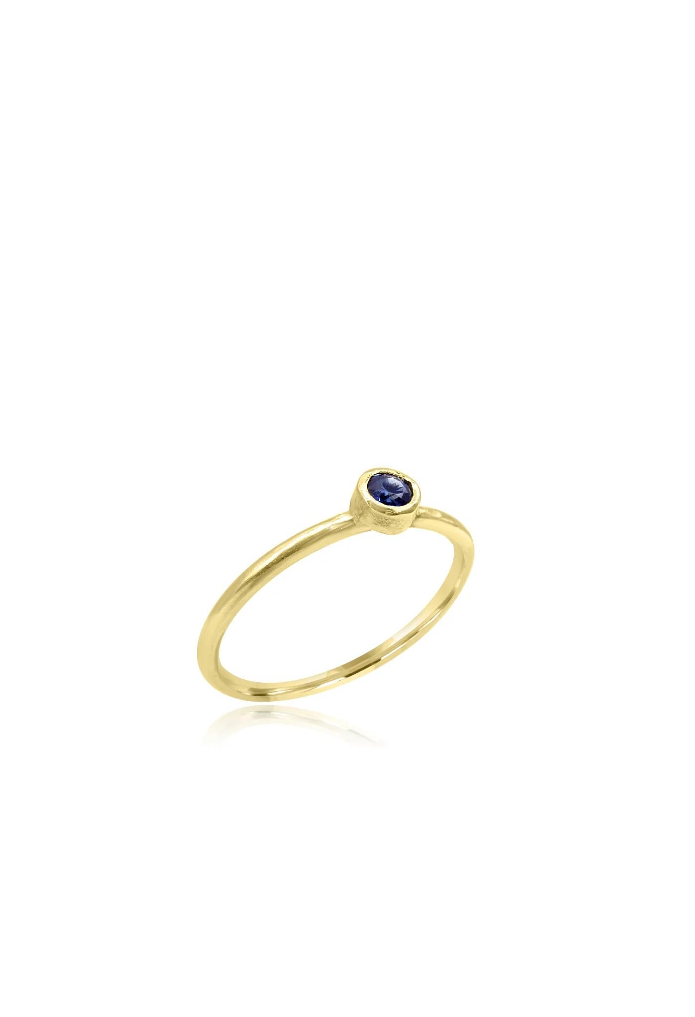 Stunning handmade ring crafted from 18 karat textured gold in Cornwall. The thin band features a unique texture, adding depth and character to the design. At the centre, a beautifully set round-cut blue sapphire stone catches the eye, providing a