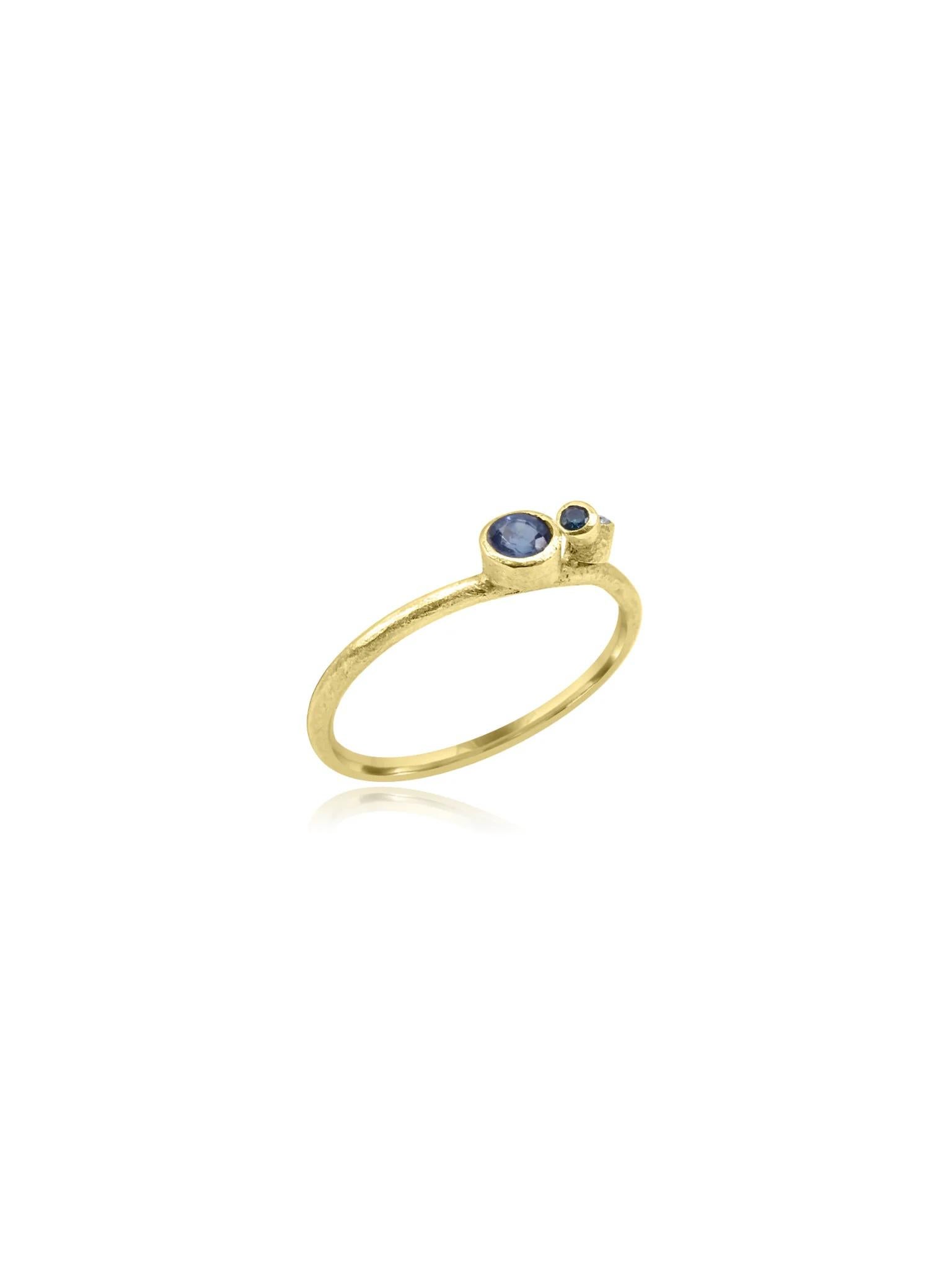 Wunderschöner handgefertigter Ring aus 18 Karat Strukturgold aus Cornwall. Das Band weist eine einzigartige Textur auf, die dem Design Tiefe und Charakter verleiht. In der Mitte bilden wunderschön gefasste blaue Saphire im Rundschliff und ein