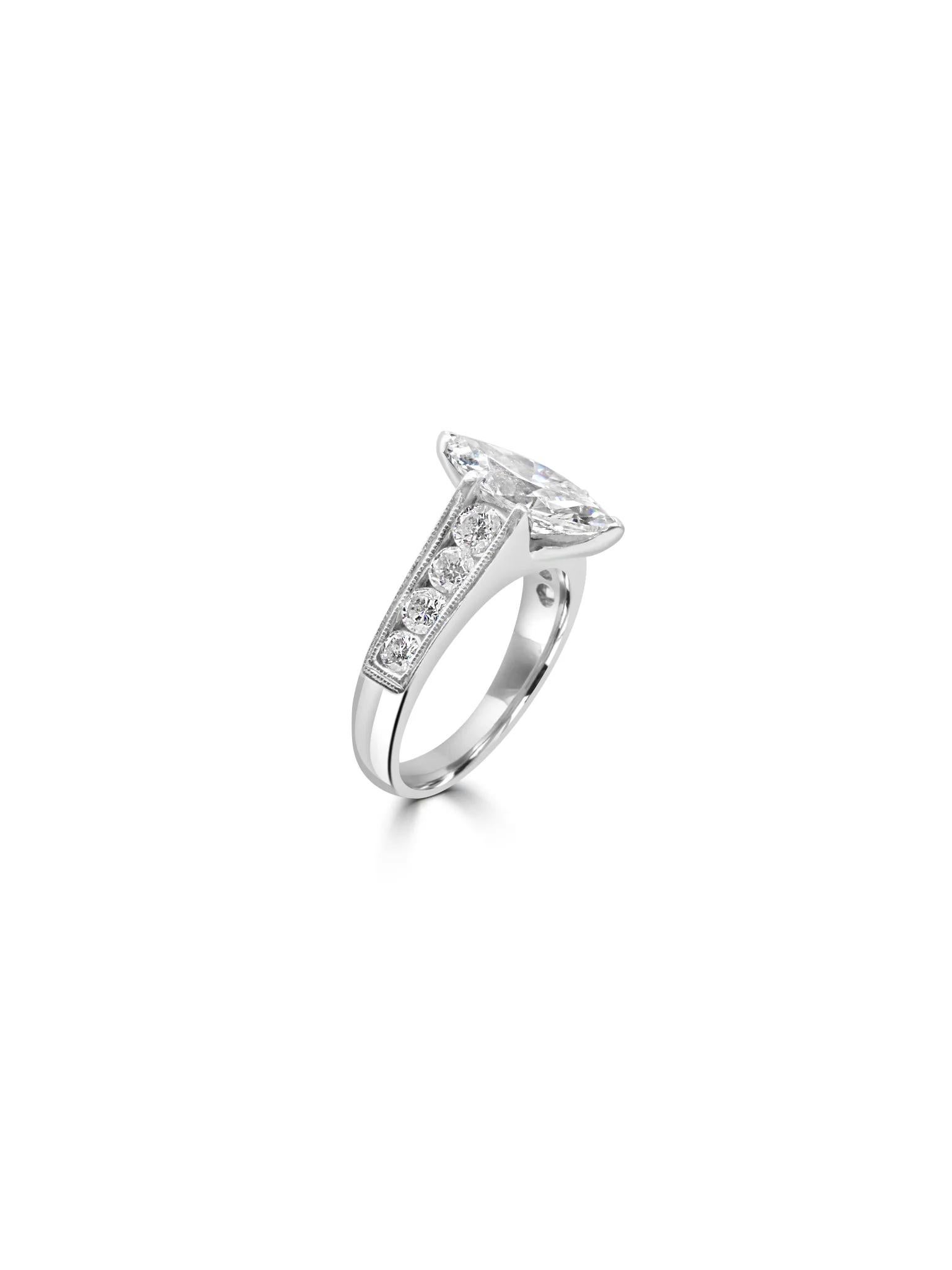 Eleganter Ring aus 18 Karat Weißgold mit aufwändigen Details entlang des Rings. In der Mitte befindet sich ein atemberaubender, marquiseförmiger Diamant, der durch kleinere Diamanten auf der Hälfte des Bandes ergänzt wird und diesem exquisiten Stück