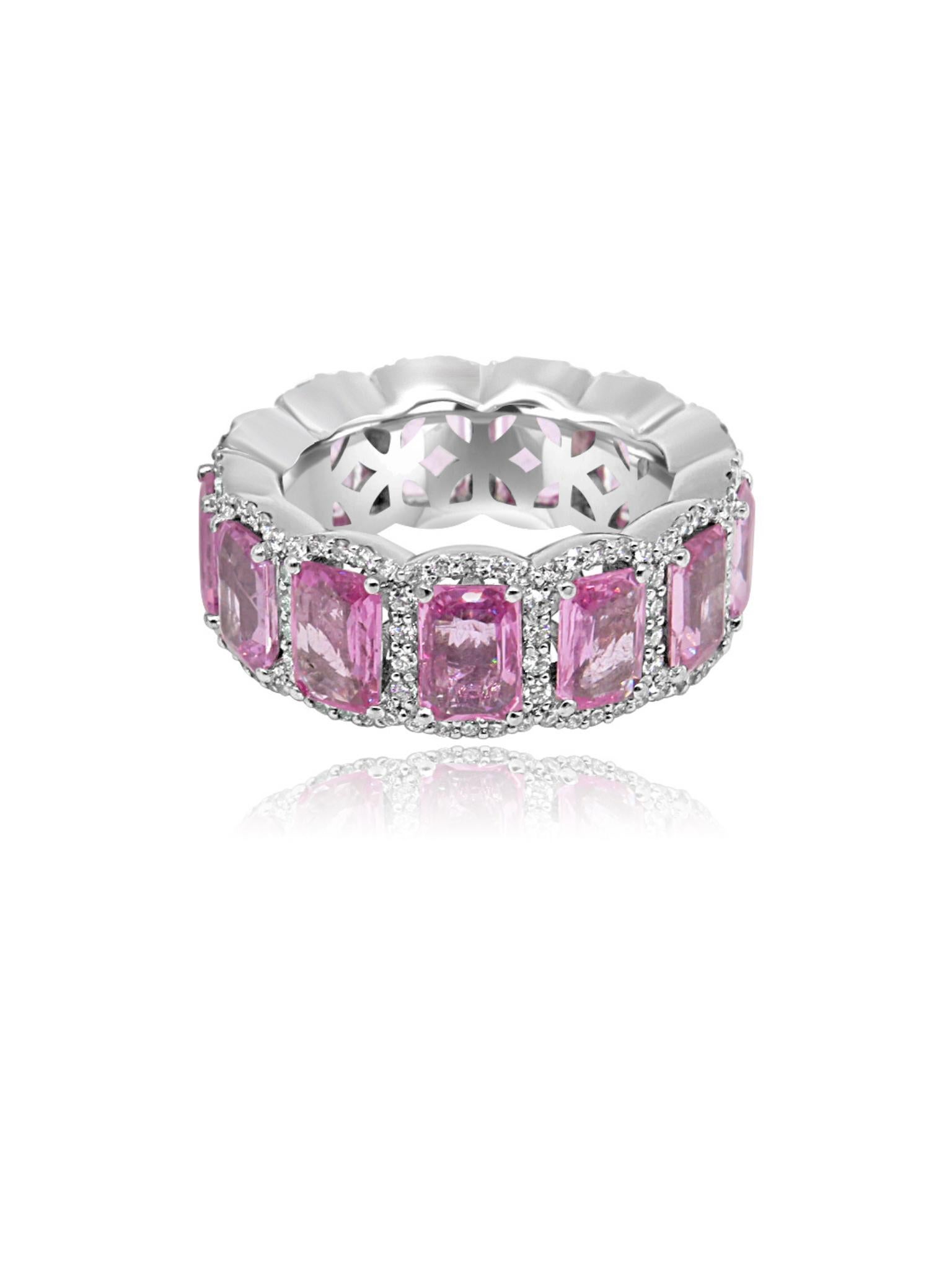 Elegant eternity ring crafted from 18-karat white gold. The ring features a series of pink emerald-cut sapphires, each framed by a halo of diamonds. The sapphires are arranged in a continuous band, symbolising eternity, with the vibrant pink stones