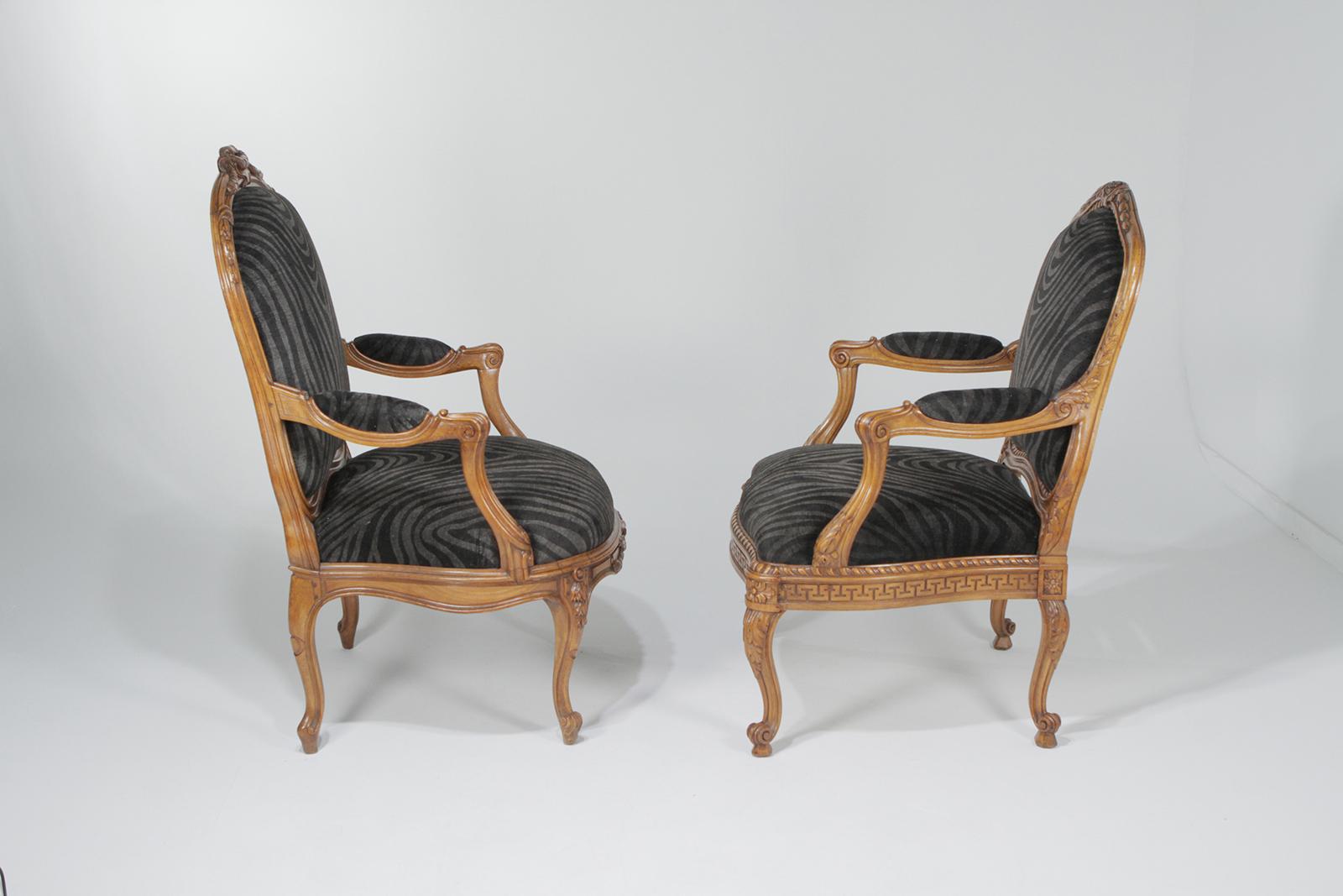 Sizzling hot pair of Mr. and Ms. antique carved walnut armchairs having French pegged construction and fabulous cut velvet faux zebra grey and black upholstery. The chairs intentionally do not match, which makes them especially chic. The color of