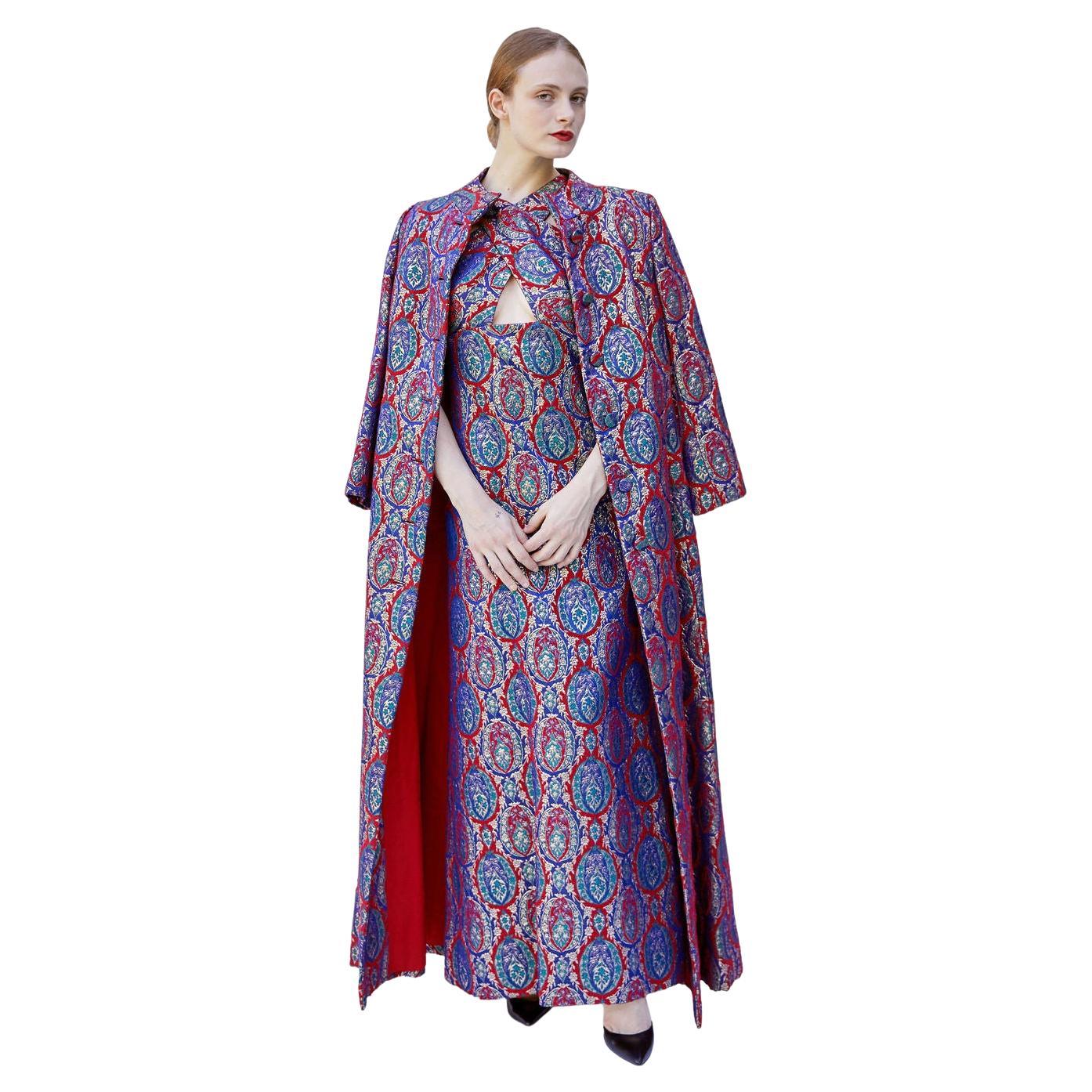 Eleva il tuo guardaroba invernale con l'abito in broccato rosso e viola Mr. Blackwell Custom 1960's W/coat. Realizzato in un vivace tessuto rosso e viola, questo set di cappotto e abito coordinato è perfetto per qualsiasi evento formale. Con la sua