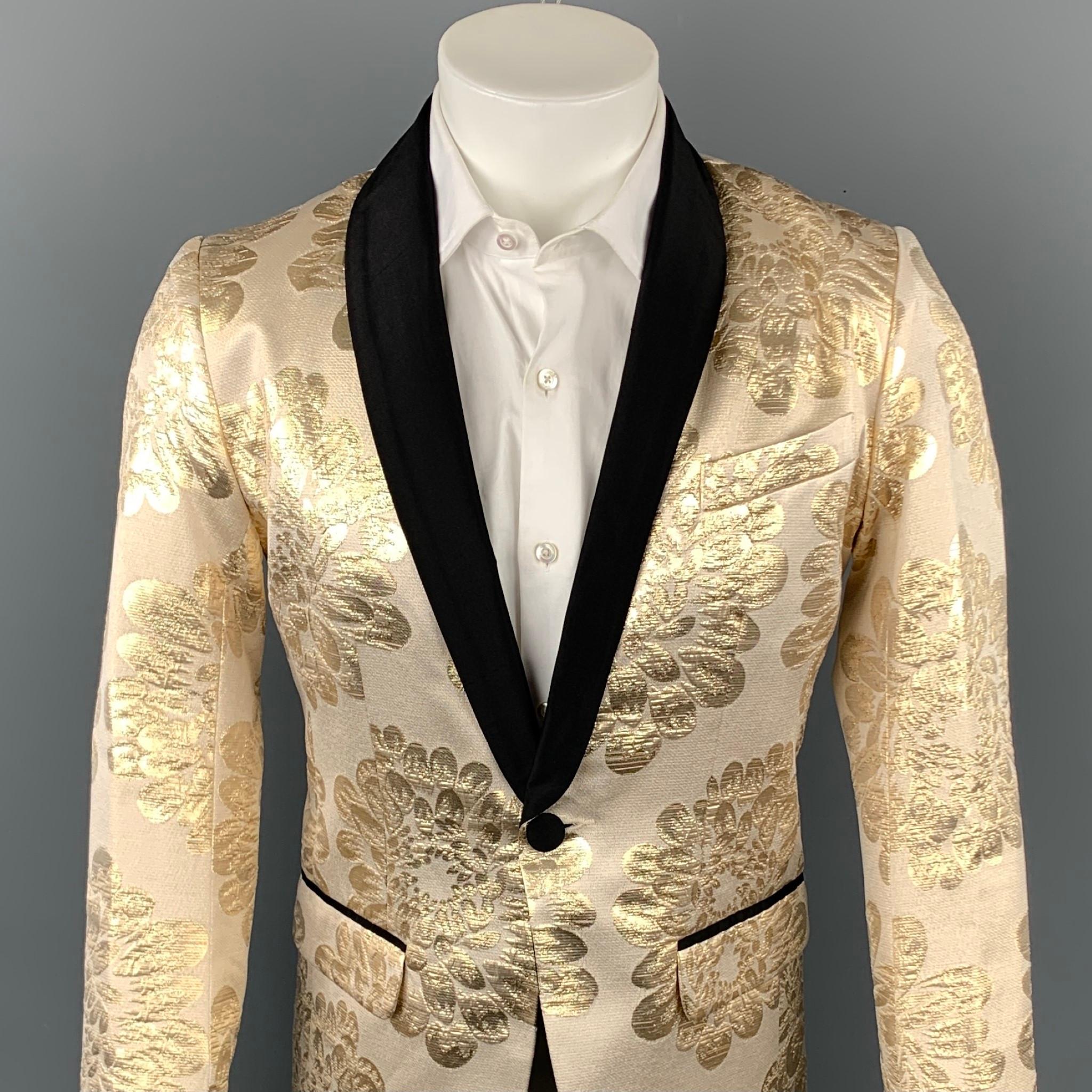 MR TURK sport coat comes in a beige & gold brocade cotton with a full liner featuring a shawl lapel, flap pockets, and a single button closure. Made in USA.

Very Good Pre-Owned Condition.
Marked: 36

Measurements:

Shoulder: 16.5 in.
Chest: 36