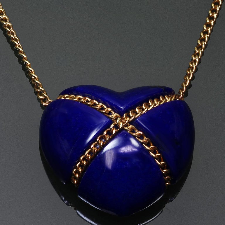 This stunning vintage necklace features a blue heart-shaped pendant crafted in lapis lazuli accented with a cross-over chain crafted in 18k yellow gold. Made in United States circa 1980s. Measurements: 0.55