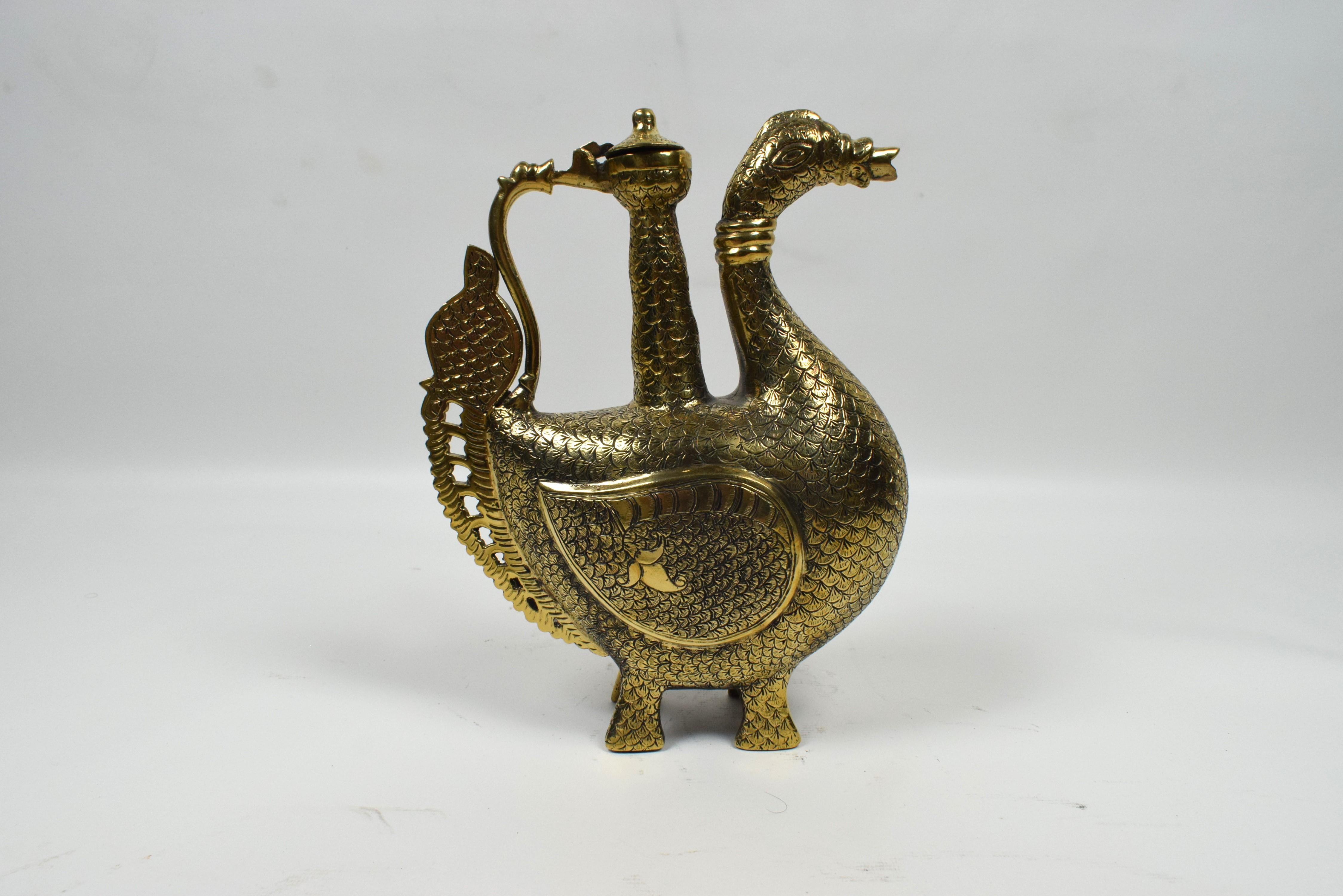 The ewer, a ceremonial pitcher, is shaped in the form of a majestic peacock, a significant motif in Mughal art symbolizing beauty, grace, and regality. The body of the ewer is crafted from high-quality brass, a metal often favored by Mughal artisans