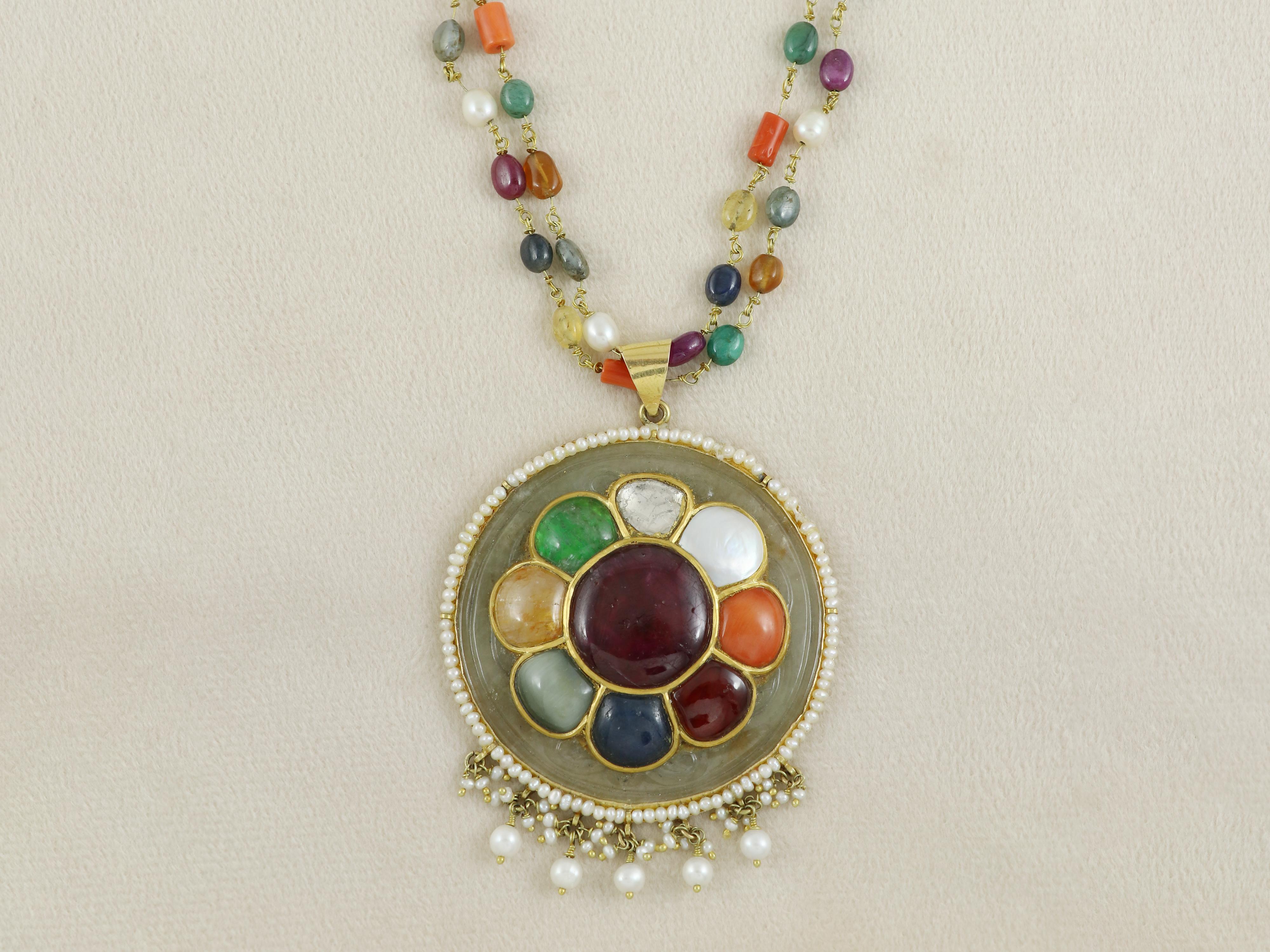 This unique Mughal antique heritage piece is a testament to fine luxury indian jewellery.A nephrite jade round pendant inlaid with all nine precious gemstones with a Bangkok ruby at centre surrounded with flat uncut diamond polki at top followed by