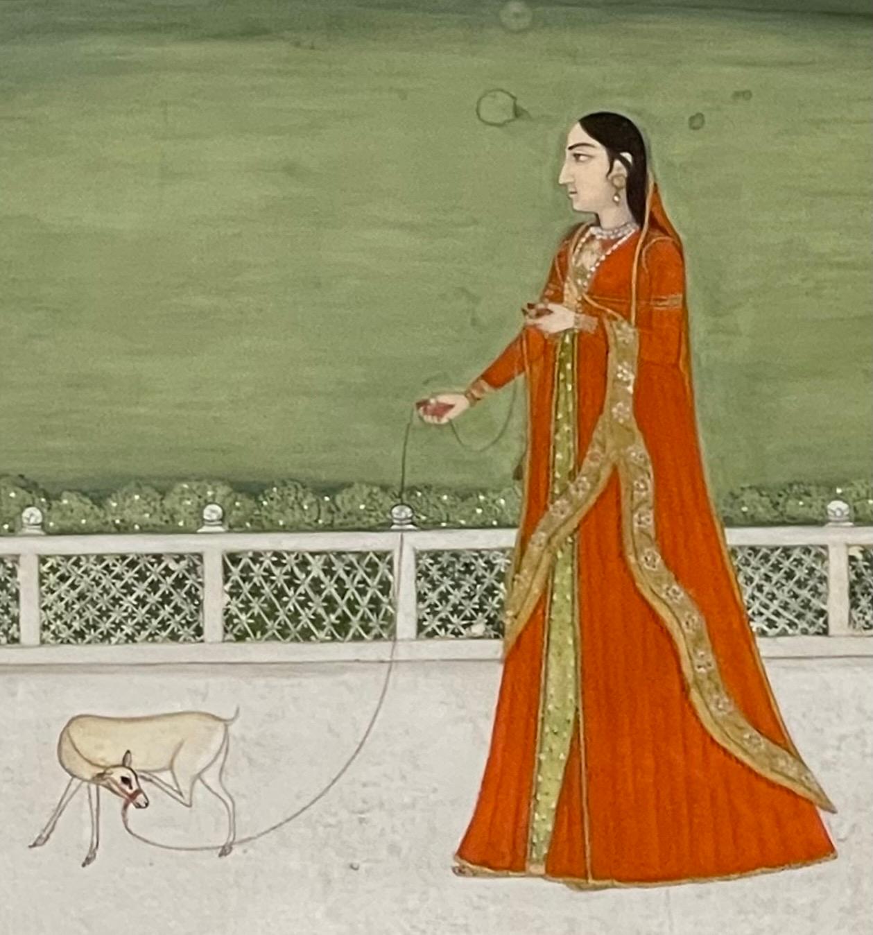 Diese Mughal-Miniatur wurde an einem der indischen Fürstenhöfe gemalt. Es zeigt eine rabenschwarze Prinzessin in einem goldverzierten safranfarbenen Seidensari. Unter einem düsteren Abendhimmel trödelt sie auf einer weißen Marmorterrasse mit einem