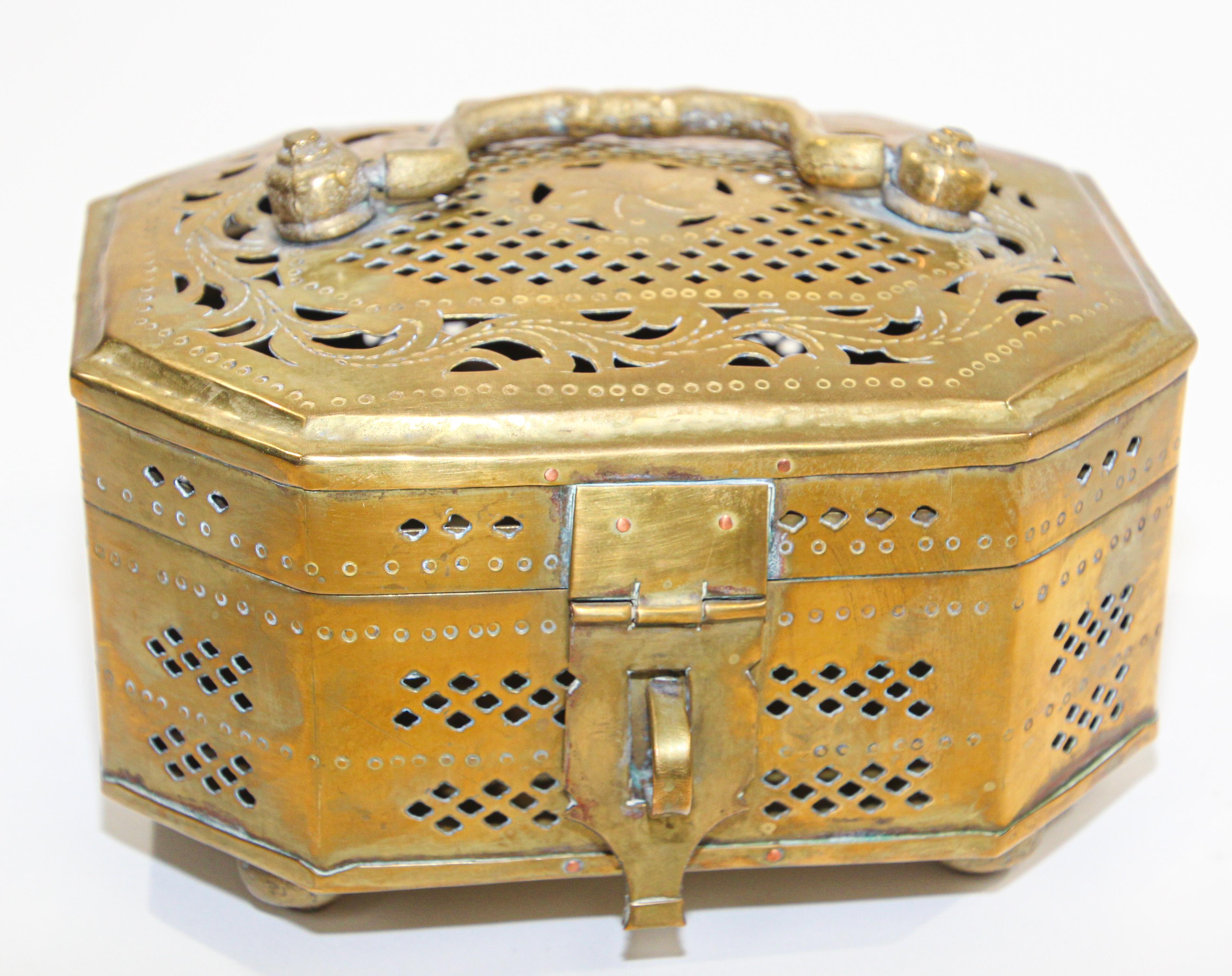 Beautiful hand-crafted polished brass footed box with with lid, latch and handle intricately hand-hammered with geometric designs and pierced with holes. 
Vintage pierced decorative Mughal Indian style brass box from India, used to burn incense.