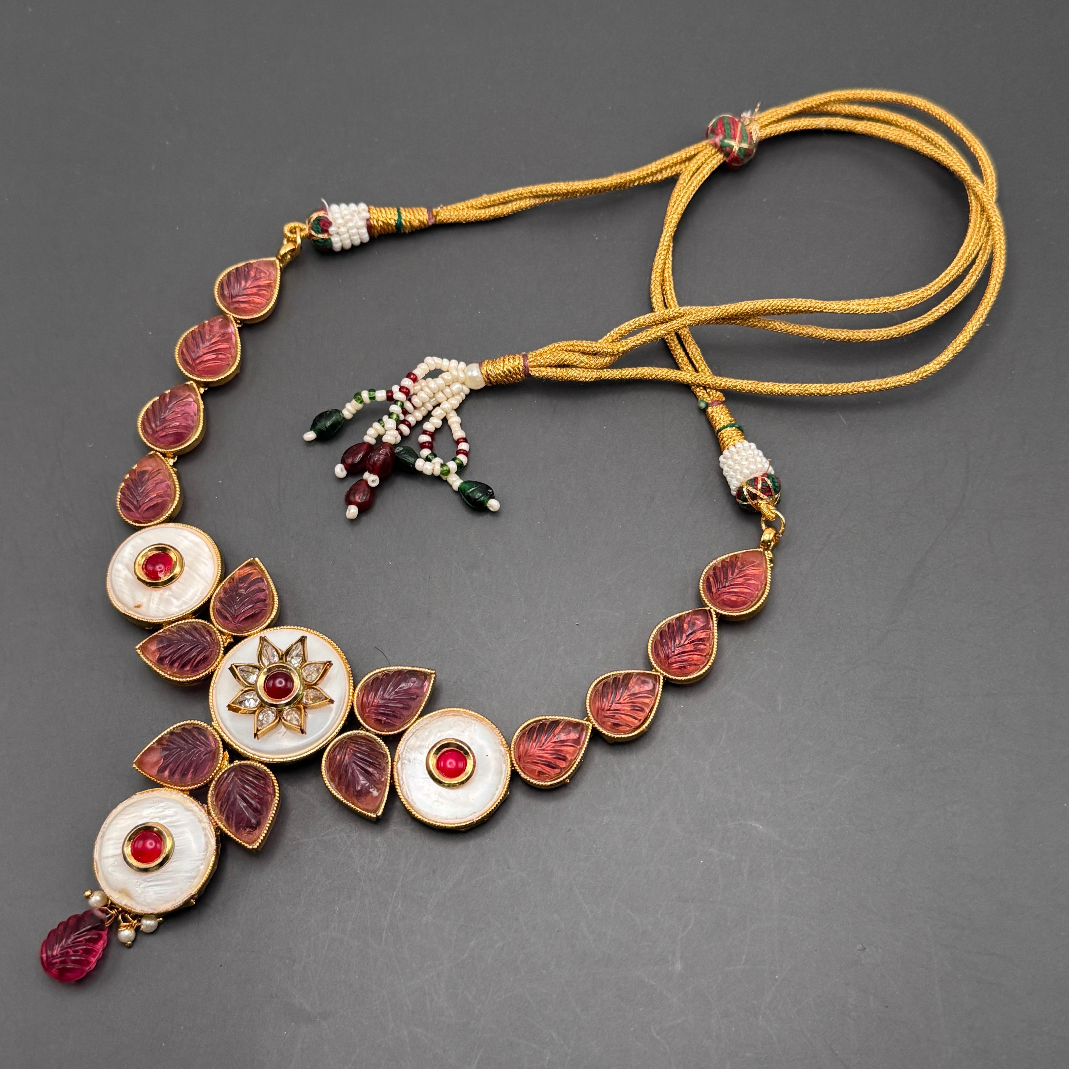 Esempio mozzafiato di arte ispirata ai Mughal, questa collana vintage è un vero e proprio pezzo forte. Il design presenta pannelli articolati ornati da elementi in vetro rosa a coste che imitano l'aspetto di gemme preziose, incastonate in metallo