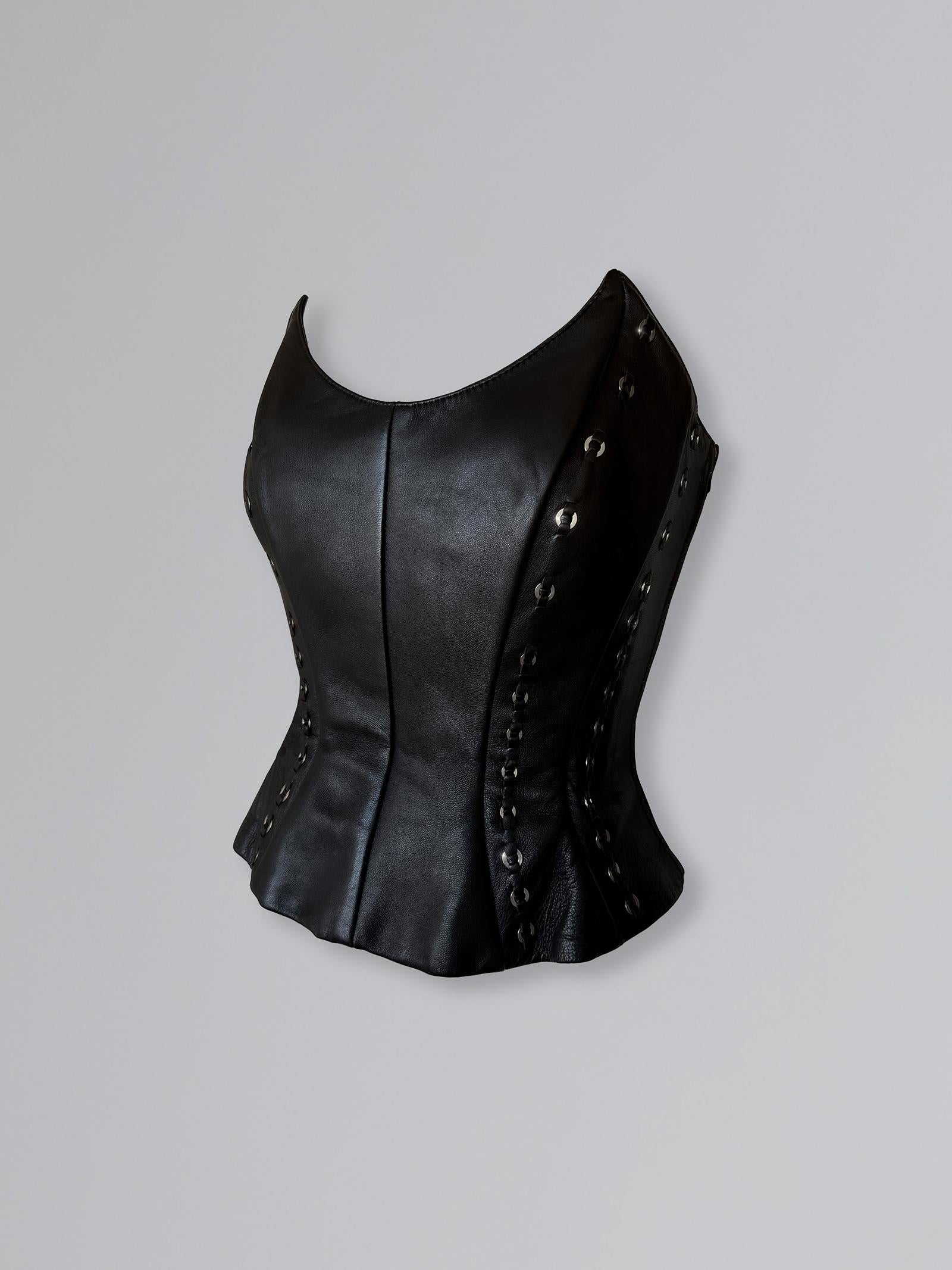 Superbe et rare top corset en cuir de la Collectional Printemps/Eté 1994. Coupé dans un cuir noir de haute qualité et d'une belle brillance, le corsage s'incurve en forme de sablier - la silhouette emblématique de Thierry Mugler. L'encolure plonge