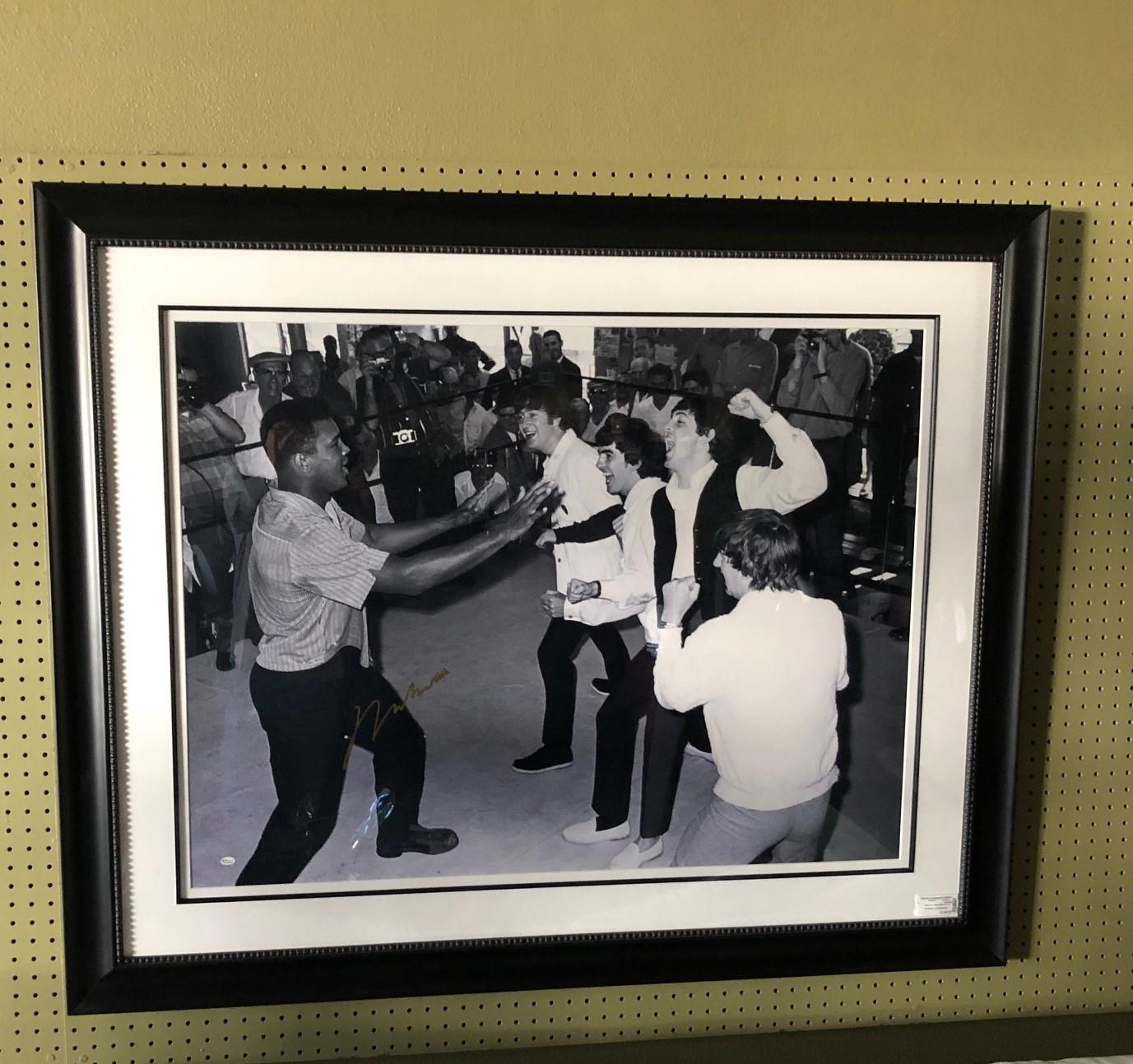Black and white photograph of Muhammad Ali (Cassius Clay) and the Beatles taken in February, 1964 in Miami Beach, Florida. The photo is signed in gold ink by Ali and is professionally matted and framed.

The photograph measures 30