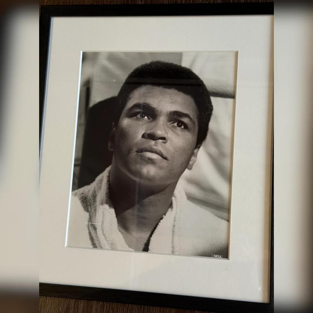 Muhammad Ali The Greatest (1977) - FRAMED
Photo Still (8 X 10 Inches)

Original b&w publicity still

A striking original 1977 black-and-white press still of Muhammad Ali, captured in a moment of quiet reflection outside the ring. Framed and