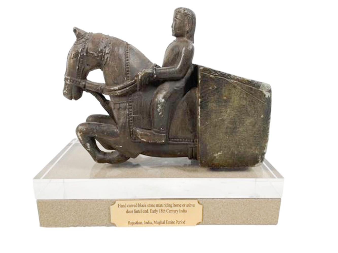 Élément architectural en pierre sculptée représentant un cavalier en uniforme à cheval dans une pose formelle. Sculptée dans un seul bloc, la sculpture en ronde-bosse représente le cheval depuis l'arrière du cavalier jusqu'à l'avant, l'encolure