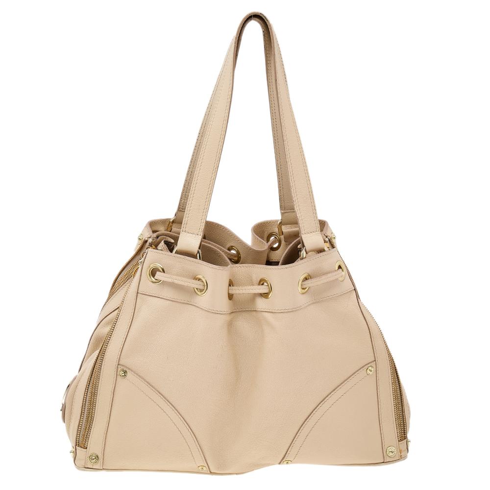 This shoulder bag from the House of Mulberry is an absolute delight! It is created using beige leather on the exterior and comes with distinct gold-toned hardware. This shoulder bag is provided with dual handles and drawstring detail. This Mulberry