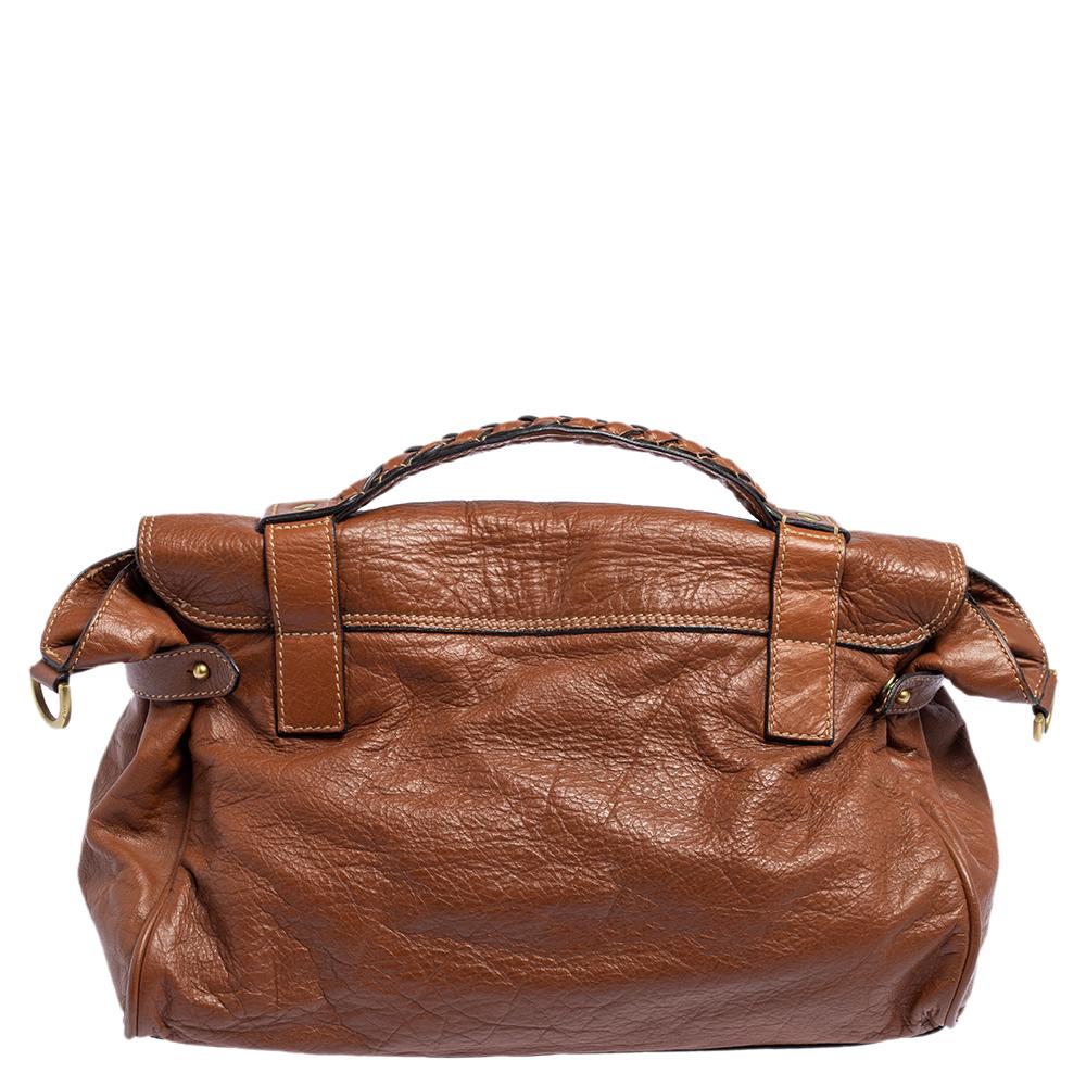 The Alexa satchel by Mulberry is crafted from brown leather and features a turn-lock closure and buckled straps on the front flap. The fabric-lined interior is designed to stow away your morning to evening essentials. It has a braided top handle and