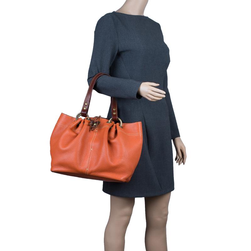 This exquisitely designed tote by Mulberry looks chic for a daily pairing up with casuals. Crafted from orange leather, this Matt Glove Judy tote bag is certainly splendid. It features contrasting handles with a minimal gold-tone detailing and