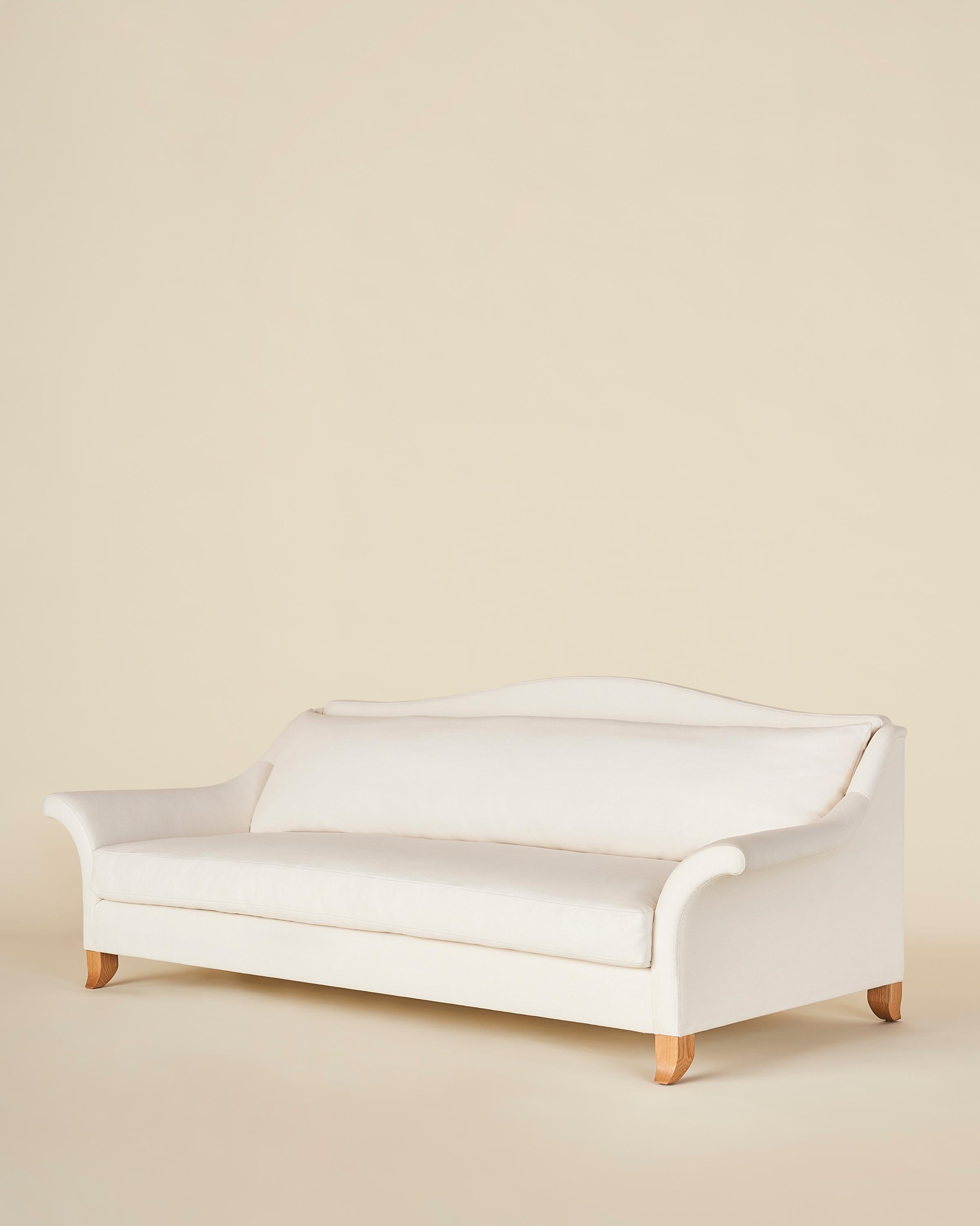 Ein klassisches Camelback-Sofa mit dramatisch ausgestellten Armlehnen und ausgestellten Beinen aus massiver Eiche. Die einzelnen Sitz- und Rückenkissen sorgen für einen nahtlosen und klaren Look. Das Stück ist aus einem massiven Eichenholzrahmen