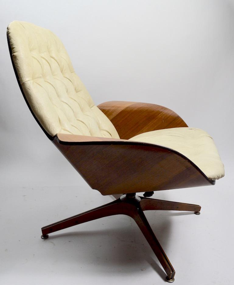 Classic design, George Mulhauser for Plycraft lounge chair and ottoman. Bent plywood shell frame, swivel and tilt lounge chair, with original footrest ottoman. This example will need to be refinished and reupholstered, but is structurally sound and