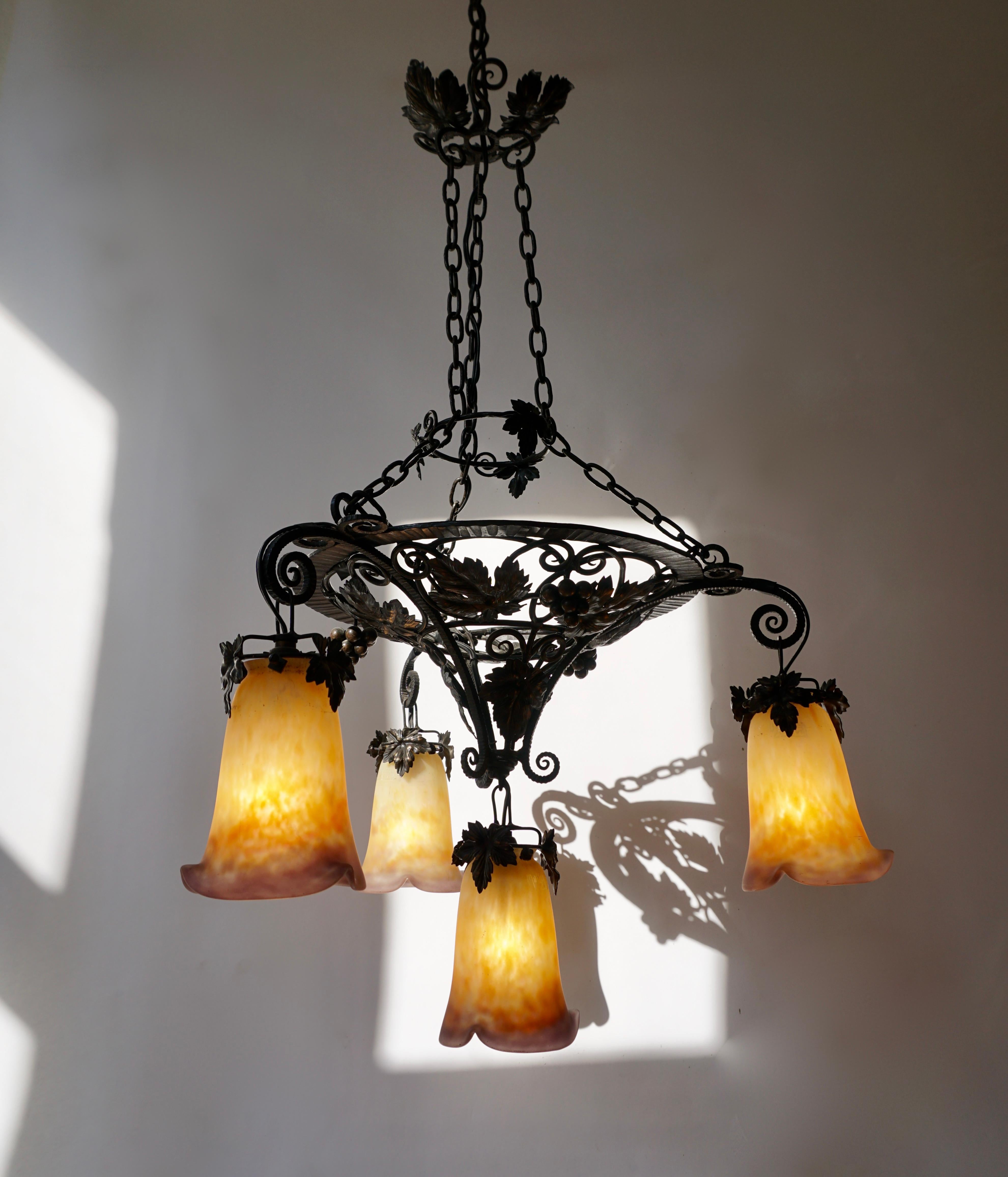 This sensational early French Art Deco chandelier was designed and signed by Muller Frères. It features a black wrought iron base with stylized floral and chain detailing. It has four frosted glass 