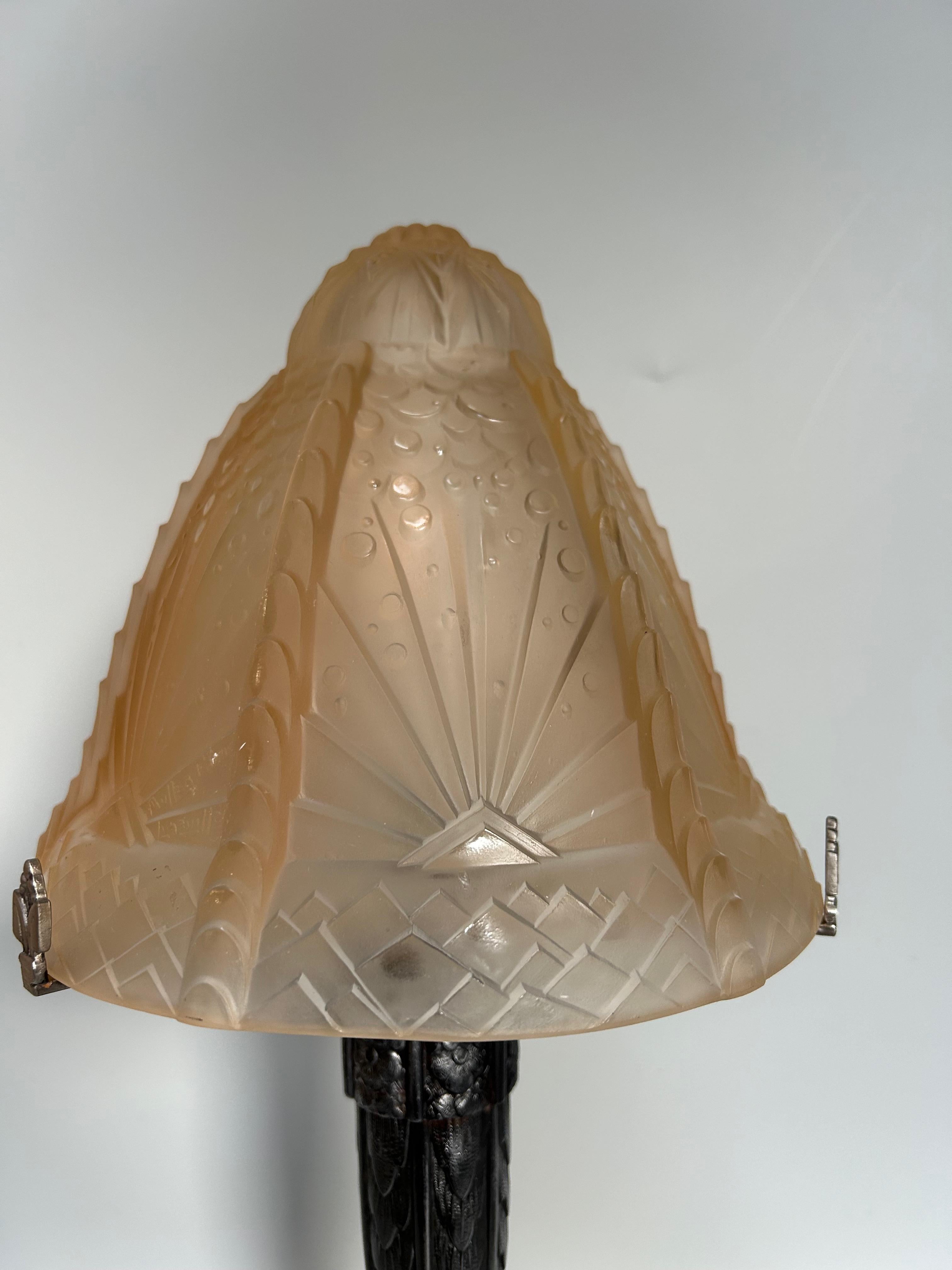 Lampe Art Déco, circa 1930.
Abat-jour en verre moulé pressé légèrement teinté, signé Muller Frères.
Base en métal avec décoration florale.
Filaire, prise B22.
En parfait état.

Hauteur : 46.5 cm
Diamètre de l'abat-jour : 23 cm
Poids : 3.5 kg

Les