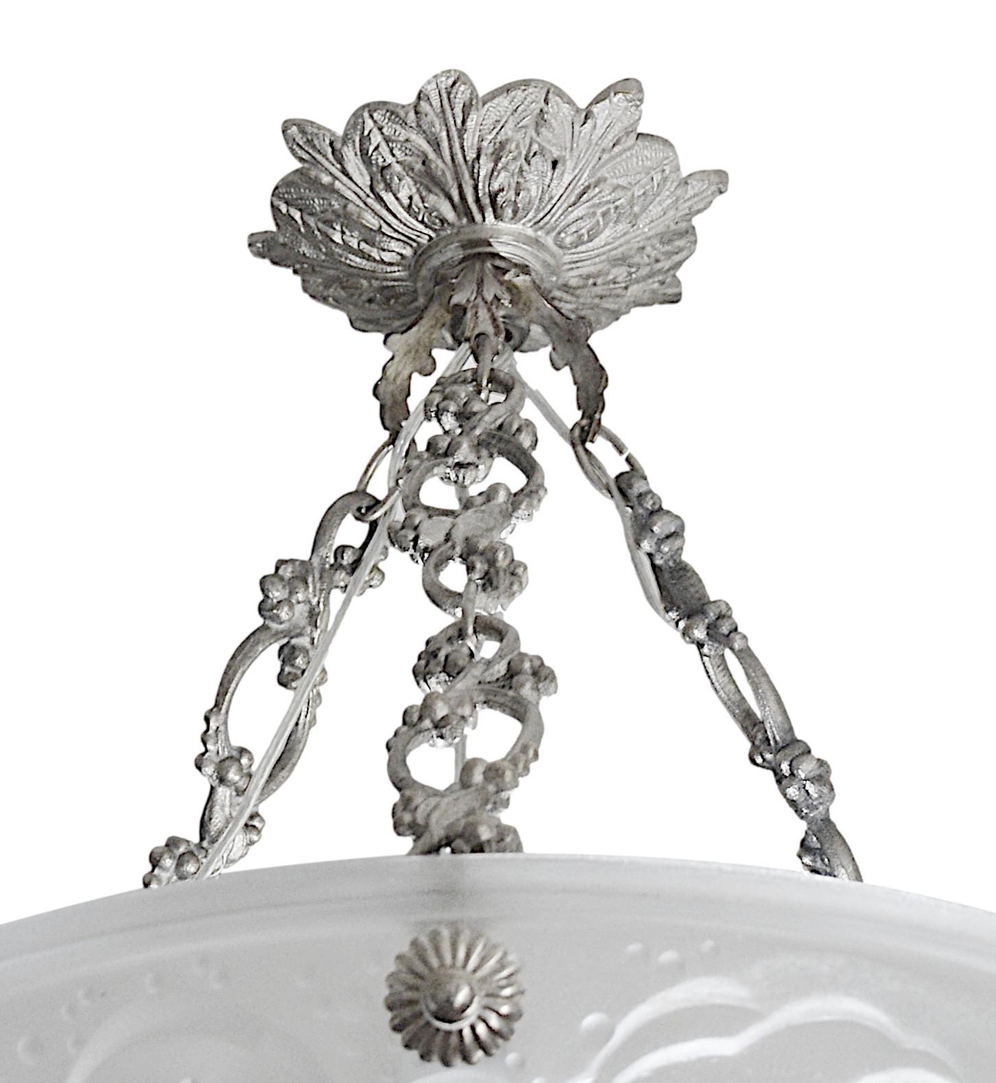 Rare, 7 shades are available. This exquisite chandelier features a stunning white frosted molded-pressed glass shade, intricately depicting six swallows in flight, set against a serene sky. The chandelier comes with a bronze fixture and is signed
