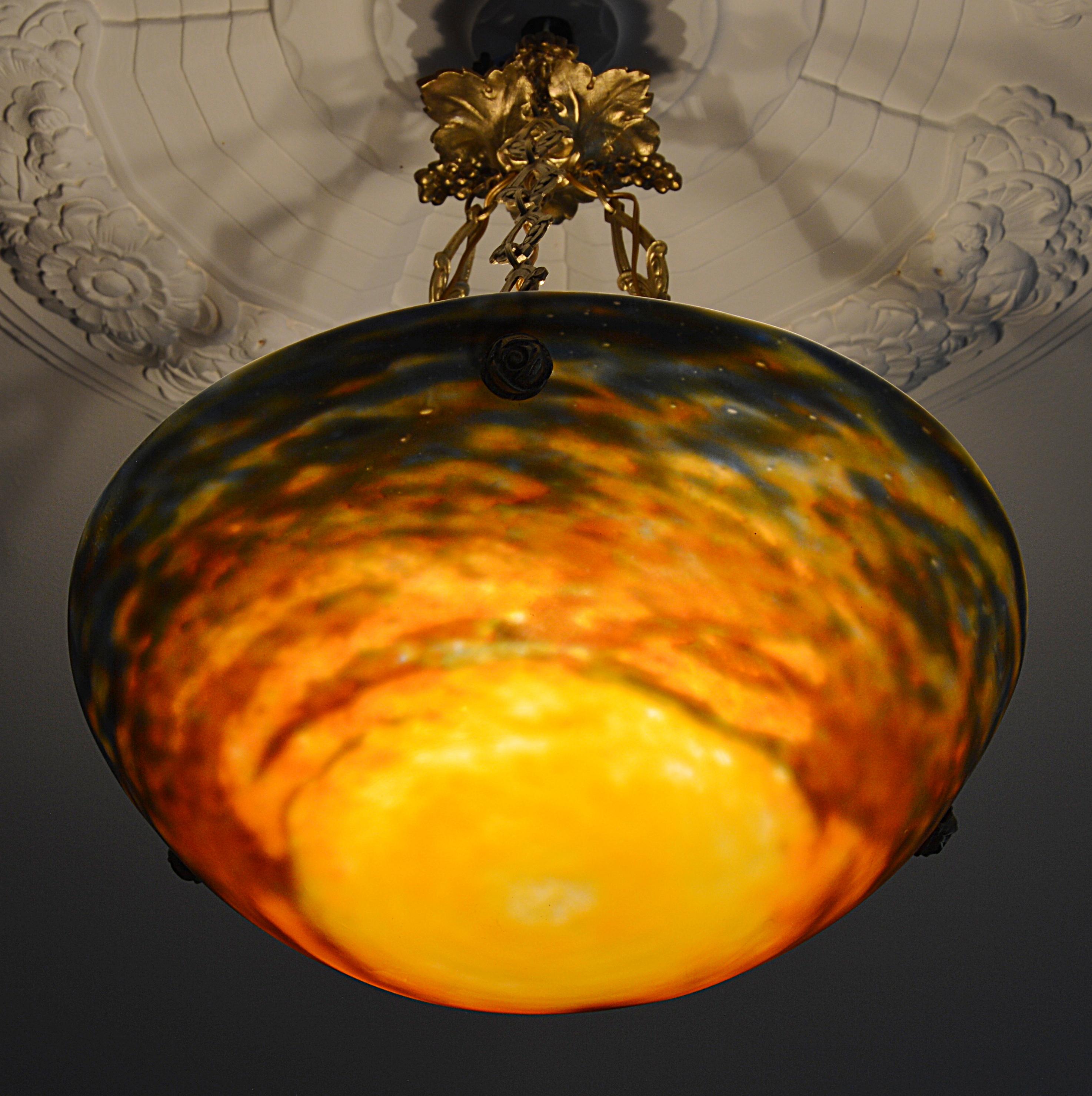 French Art Deco pendant by Muller Frères, Luneville, France, circa 1925. Mottled glass shade, powders are applied between two layers, that comes hung at its original brass fixture. Signed 