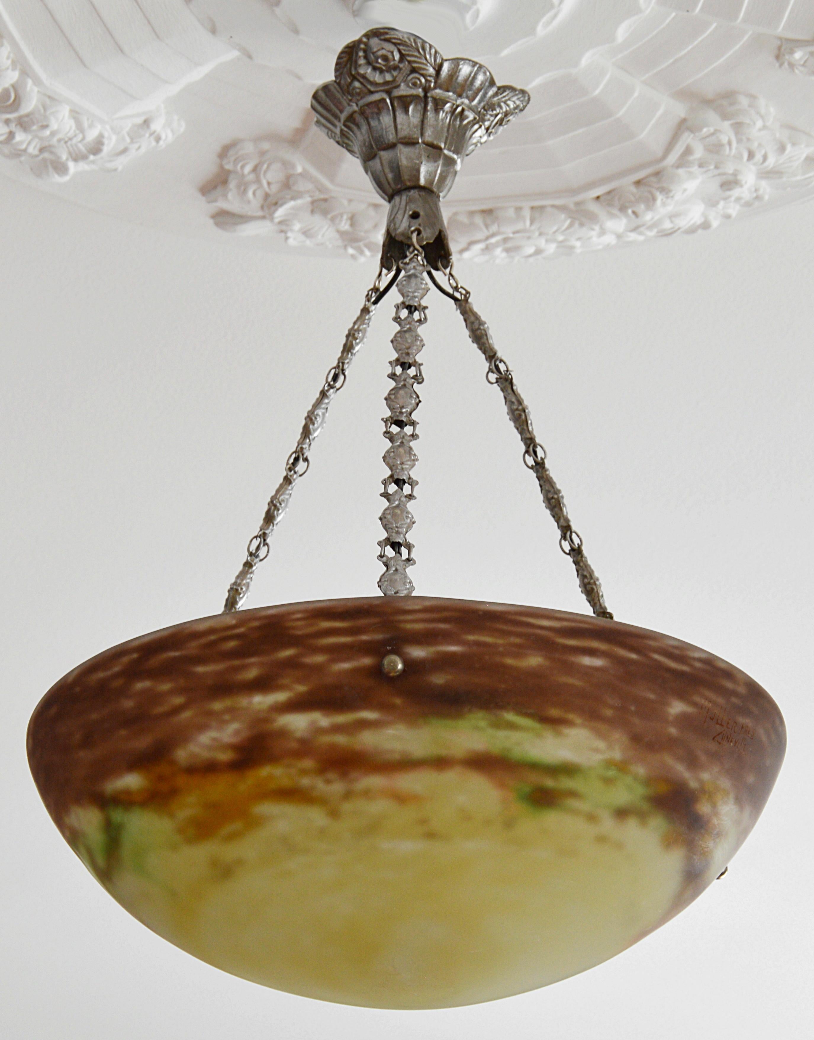 French Art Deco pendant by Muller Freres, Luneville, France, early 1920s. Mottled glass shade, powders are applied between two layers, that comes hung at its original silvered bronze (canopy and hidden-holes) and brass (chains) fixture. Signed