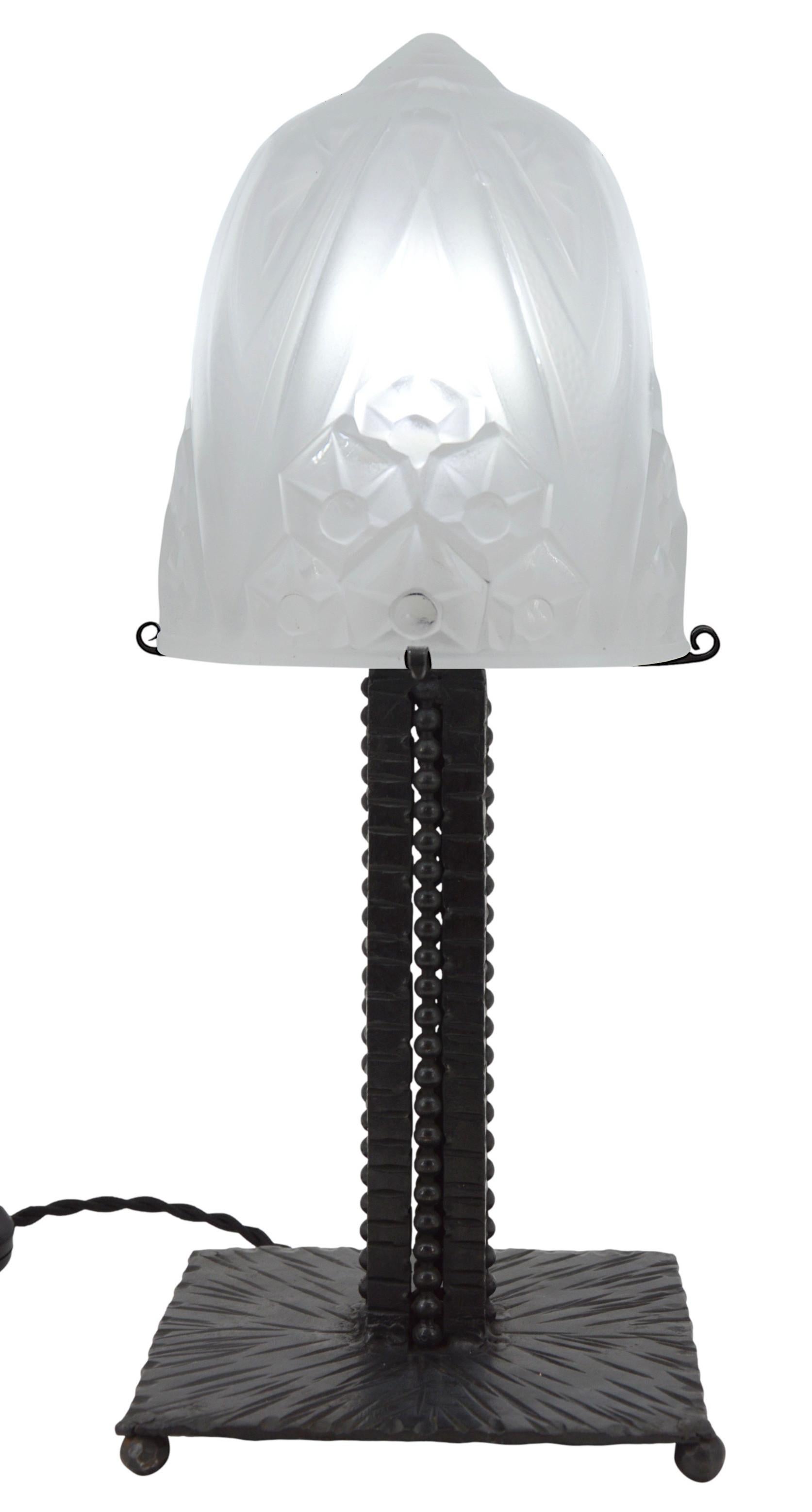 French Art Deco table lamp by MULLER FRERES, Luneville, France, 1920s. Frosted molded glass shade with a stylized flower decor on its wrought-iron base. Height : 13