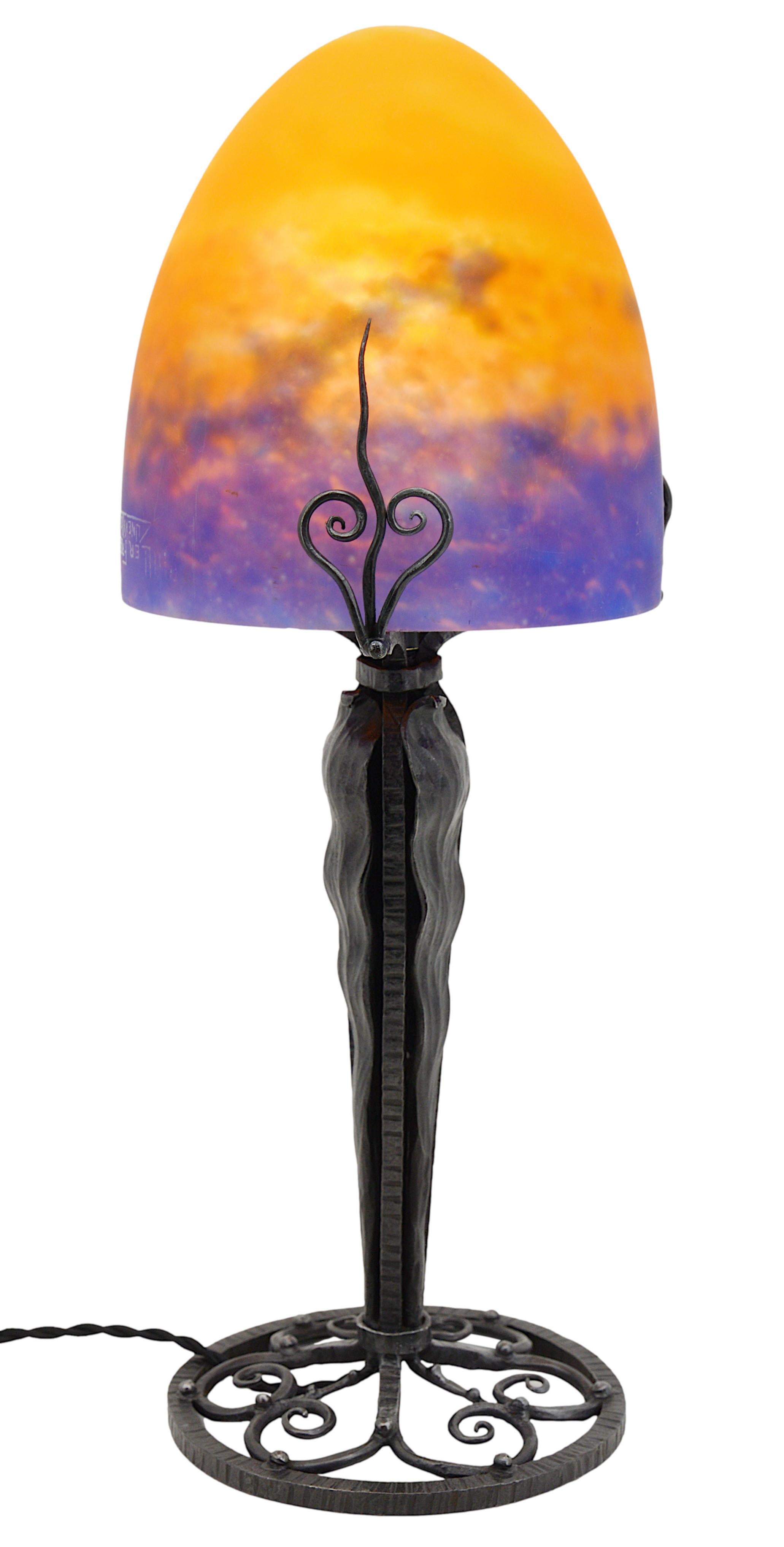 French Art Deco table lamp by Muller Freres, Luneville, France, ca.1920. Mottled glass shade, powders are applied between two layers, cut with the tool, that comes on its beautiful wrought-iron base. Colors: blue, orange and old rose. Height :