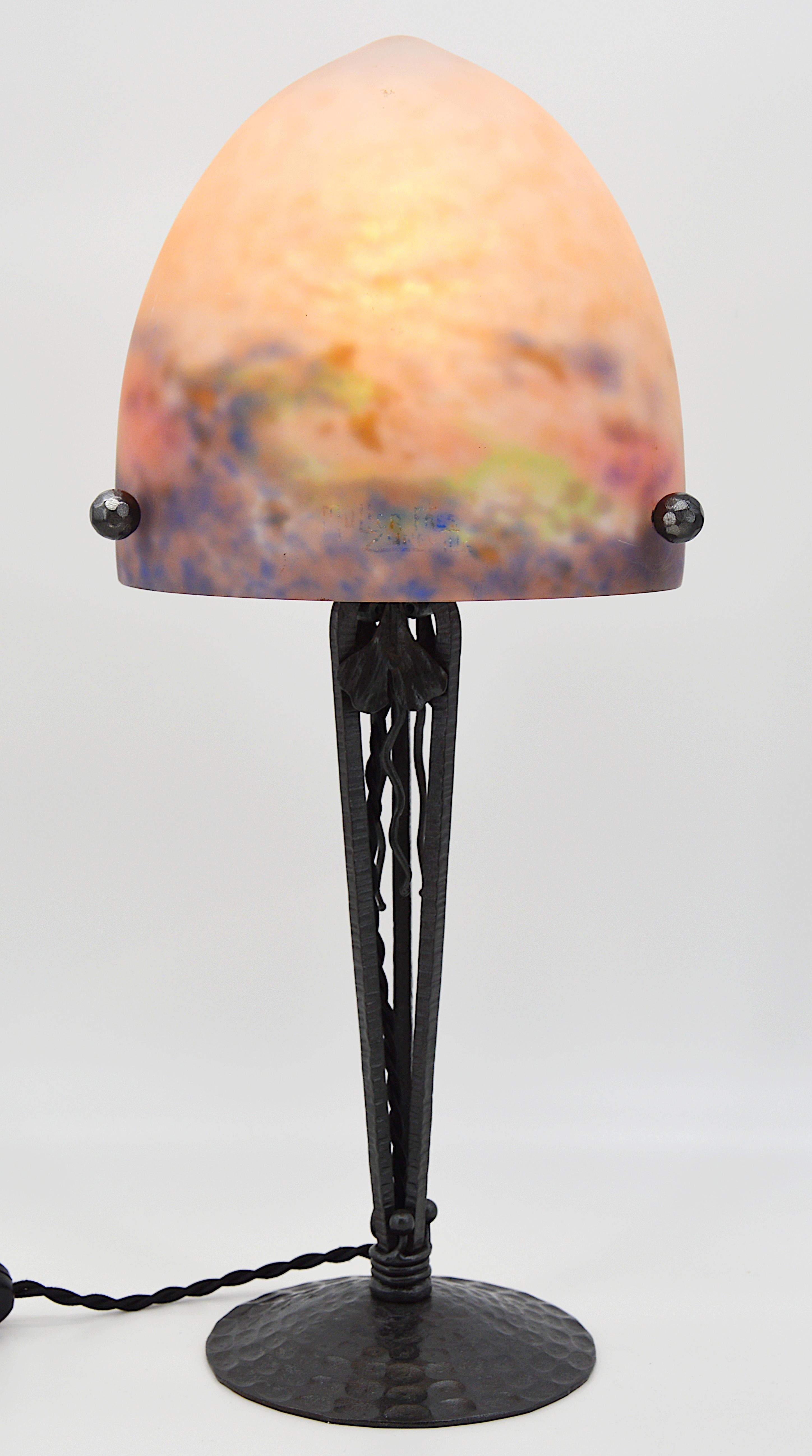 French Art Deco table lamp by Muller Frères, Luneville, France, circa 1921. Mottled glass shade, powders are applied between two layers, cut with the tool that comes on its classy wrought-iron base wit a ginkho pattern. Colors: blue, old rose, green