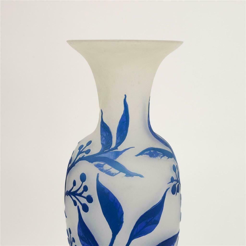 Un grand vase en verre d'art Intercalaire Art Déco Muller Frères Luneville. Un vase d'époque fantaisiste réalisé selon la difficile technique de l'intercalaire (dans laquelle le décor est inséré entre deux couches de verre).

Ce vase bleu en forme