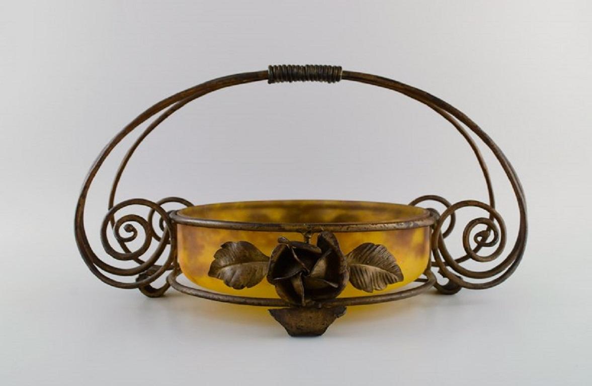 Muller Frères, Luneville. Art Nouveeau bowl in mouth-blown art glass with handle and holder in wrought iron designed with flowers and leaves. 
France, 1930s.
Measures: 46 x 32 cm.
In excellent condition.
Signed.