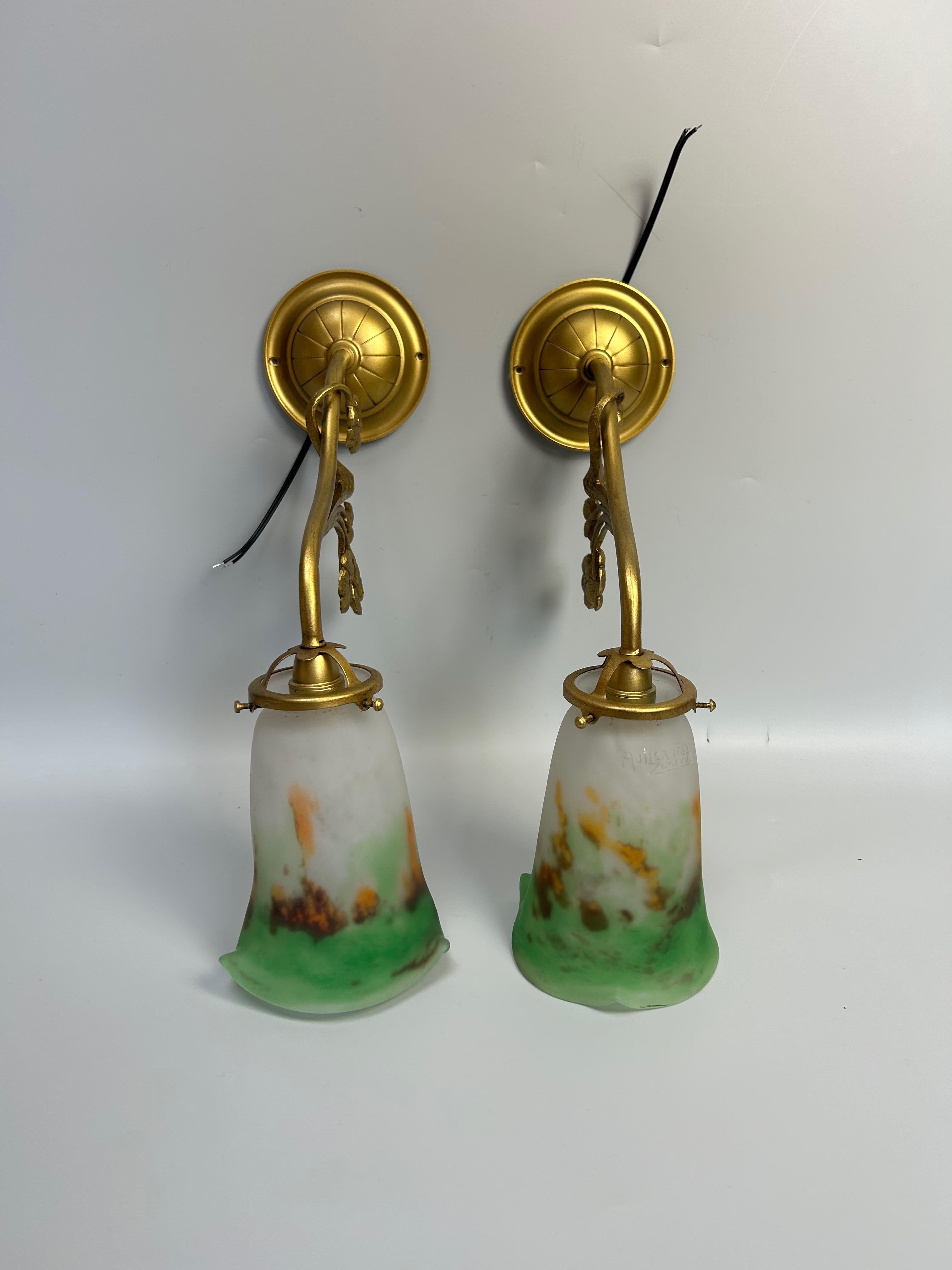 Paire d'appliques murales Art Nouveau, vers 1910.
Monture en laiton doré, abat-jour en pâte de verre signé Muller Frères Luneville.
Filaire, prise E14. Petites ampoules à visser.

En parfait état.

Hauteur totale : 36 cm
Diamètre de la base : 10,5