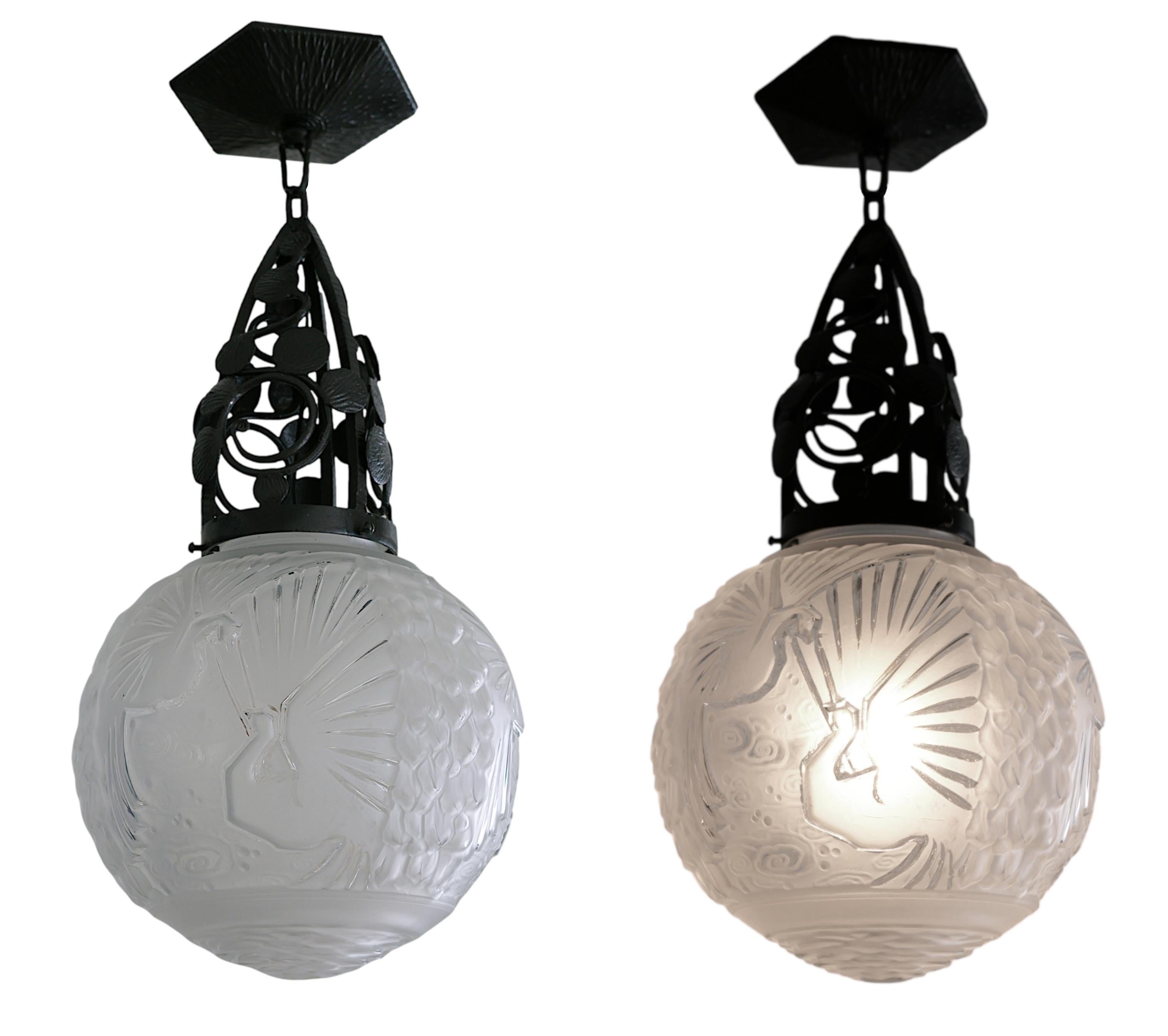 Coppia di pendenti o montature semi-incasso in stile Art Déco francese di MULLER FRERES (Luneville) e Marcel Vasseur, Francia, 1920 circa. Vetro e ferro battuto. Paralumi in vetro satinato bianco con 6 pavoni di Muller Freres. Infissi in ferro