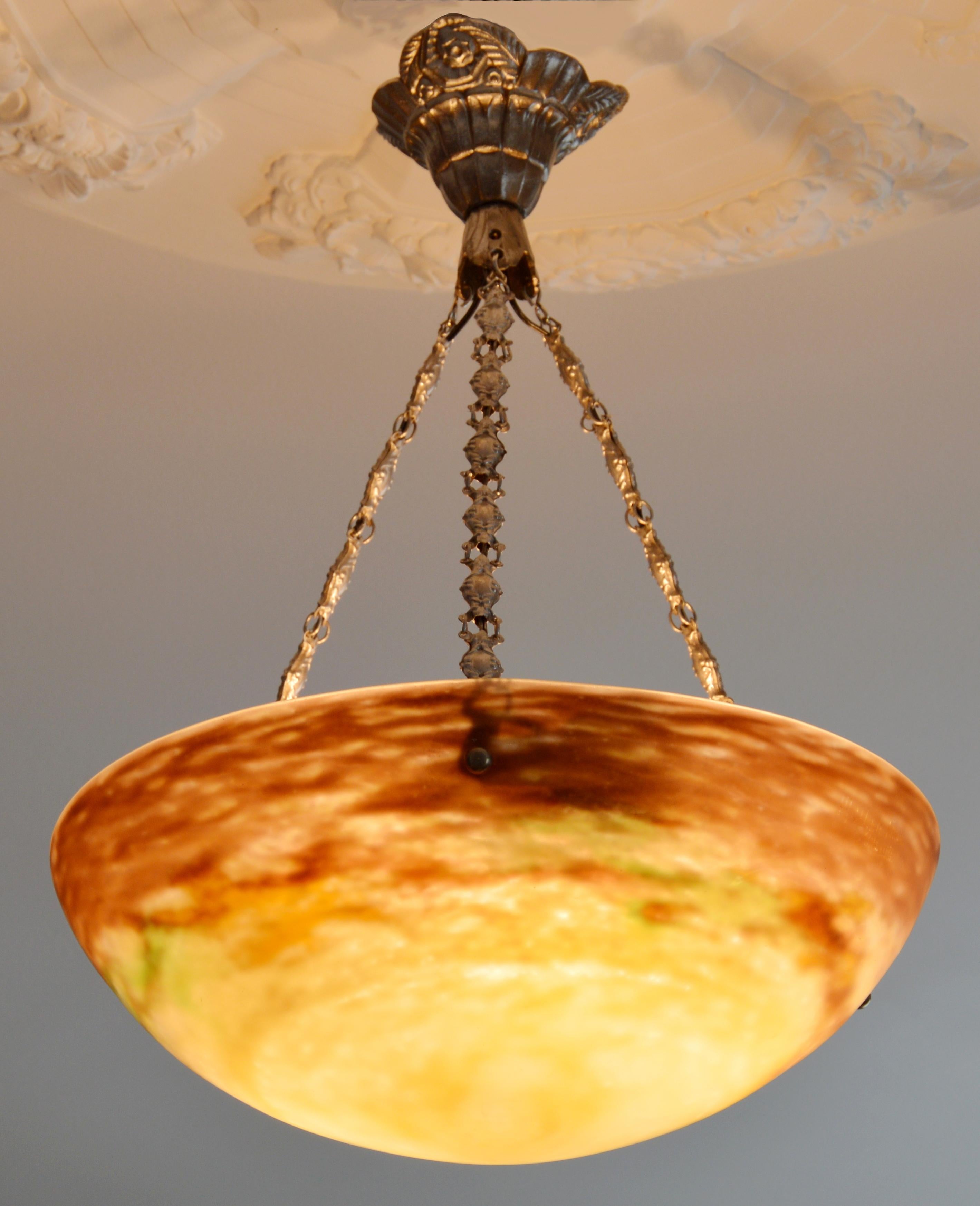 Raro e impresionante colgante Art Déco francés de Muller Frères, Luneville, Francia, de principios de los años veinte. El colgante presenta una pantalla de cristal moteado, con polvos aplicados entre dos capas, que crean un llamativo efecto